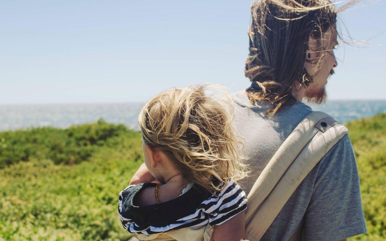 Reiseimpfung: Mann trägt Kind auf dem Rücken in der Natur