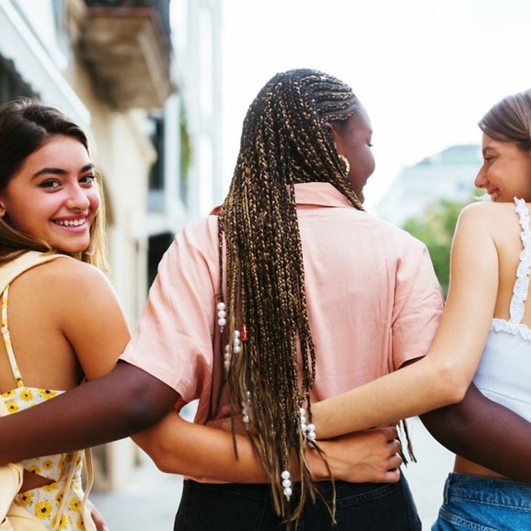 Azubi-Newsletter: Drei Freundinnen gehen Arm in Arm die Straße entlang