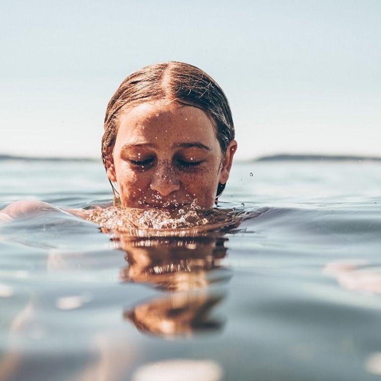 fit-Magazin: Frau badet an einem Sommertag im See