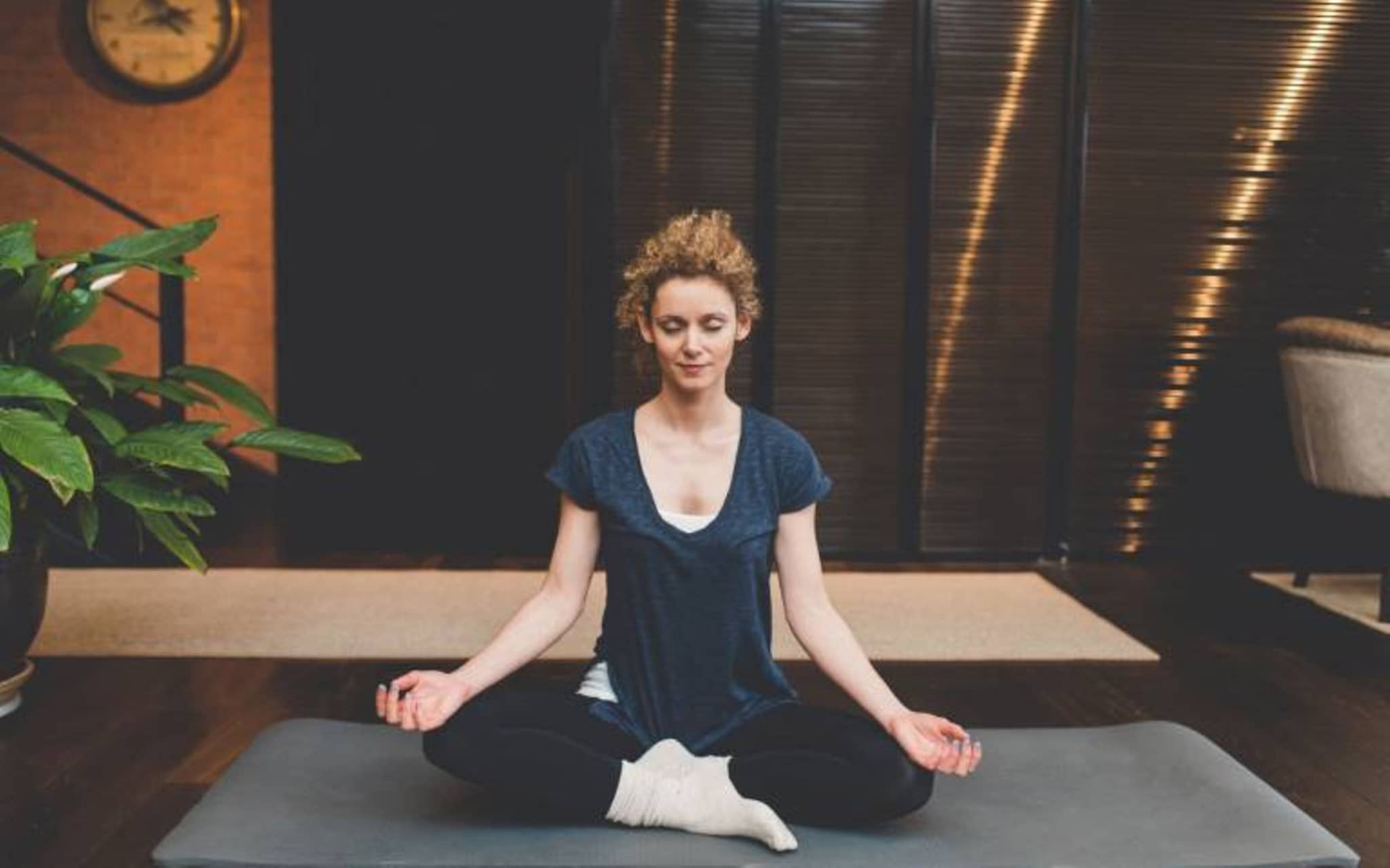 Antistress-Coaching per Balloon-App: Junge Frau meditiert im Schneidersitz