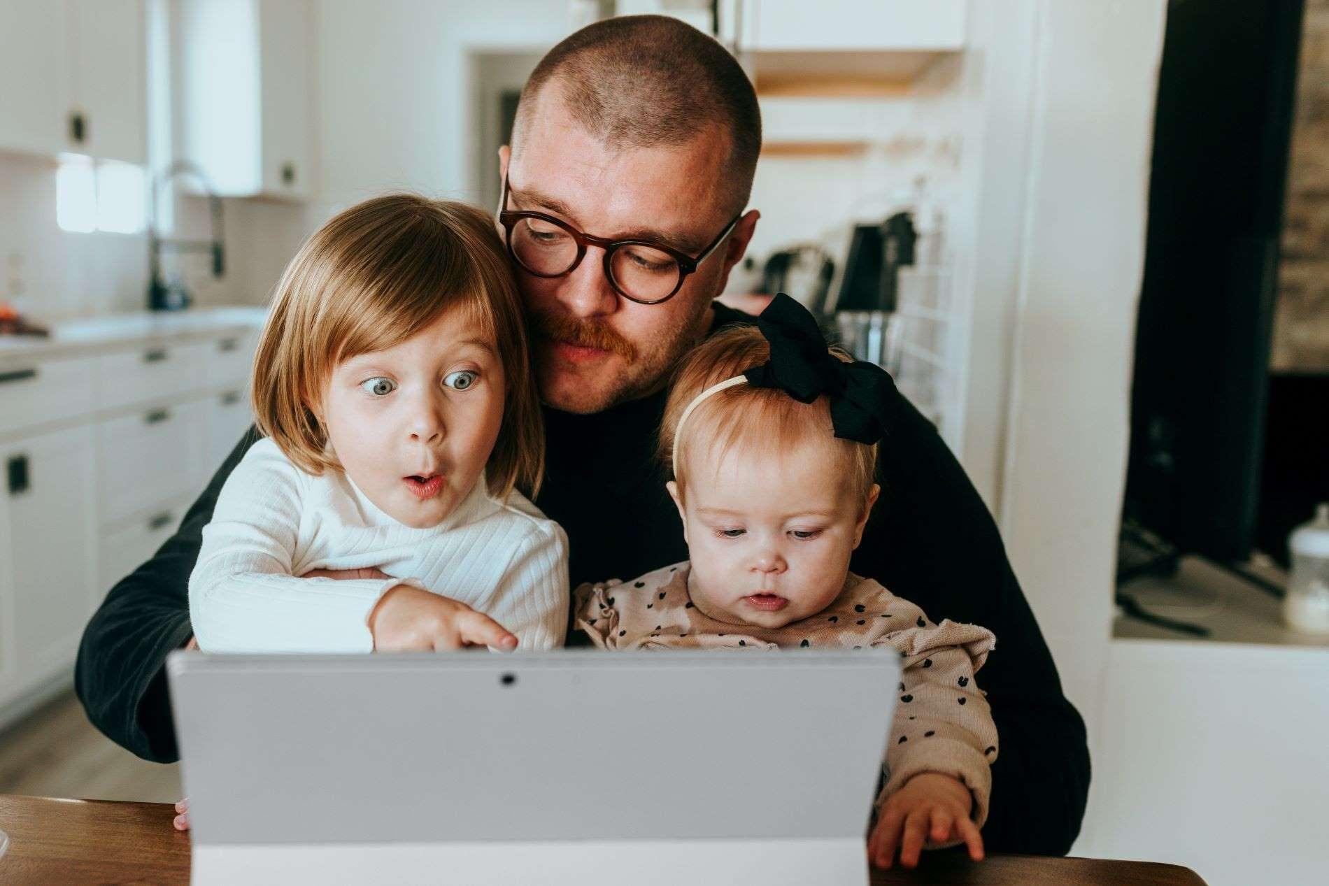 Besondere Gesundheitsleistungen: Vater mit kleinen Kindern auf dem Schoß schaut auf ein Notebook.