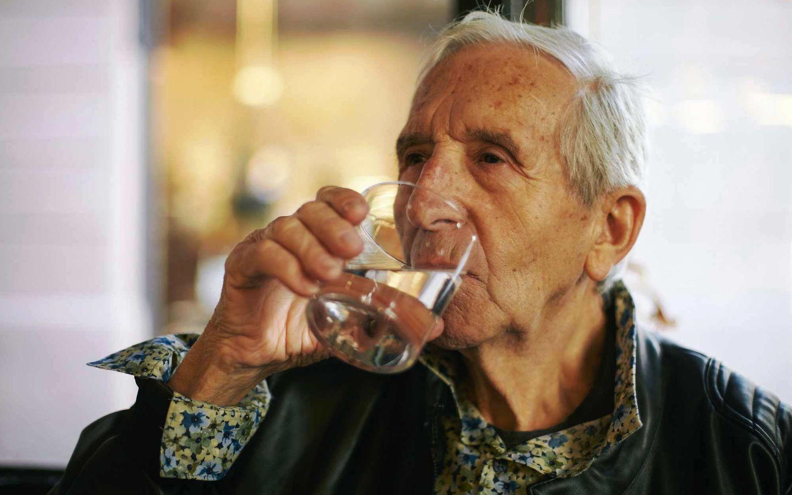 Prostatabeschwerden: Älterer Mann trinkt ein Glas Wasser.