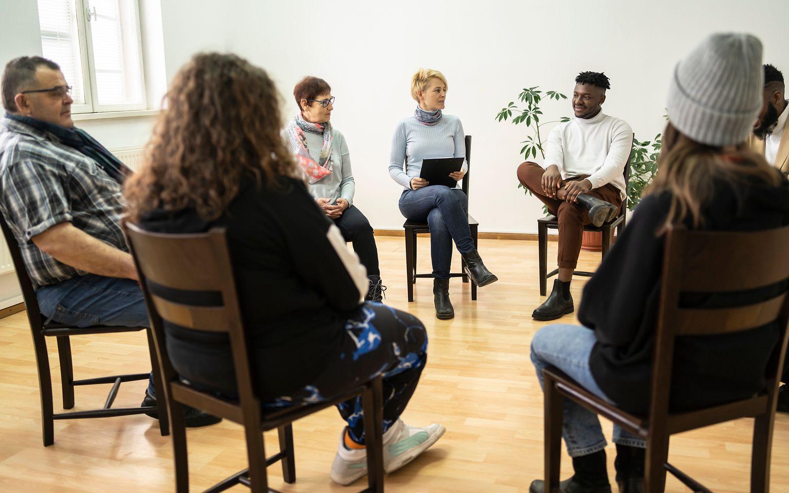 Bild: Personen sitzen in einem Stuhlkreis zur Gruppentherapie.