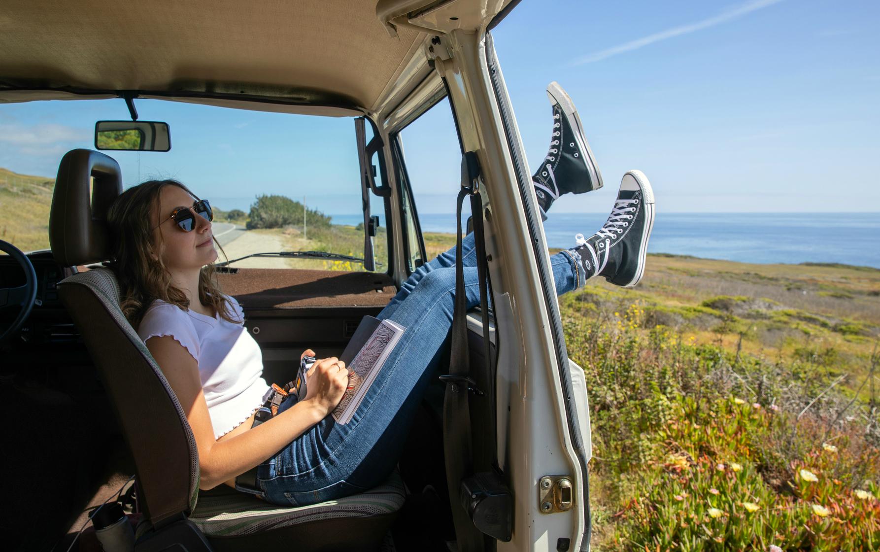 Auslandskrankenschein: Junge Frau entspannt im Minivan inmitten der Natur