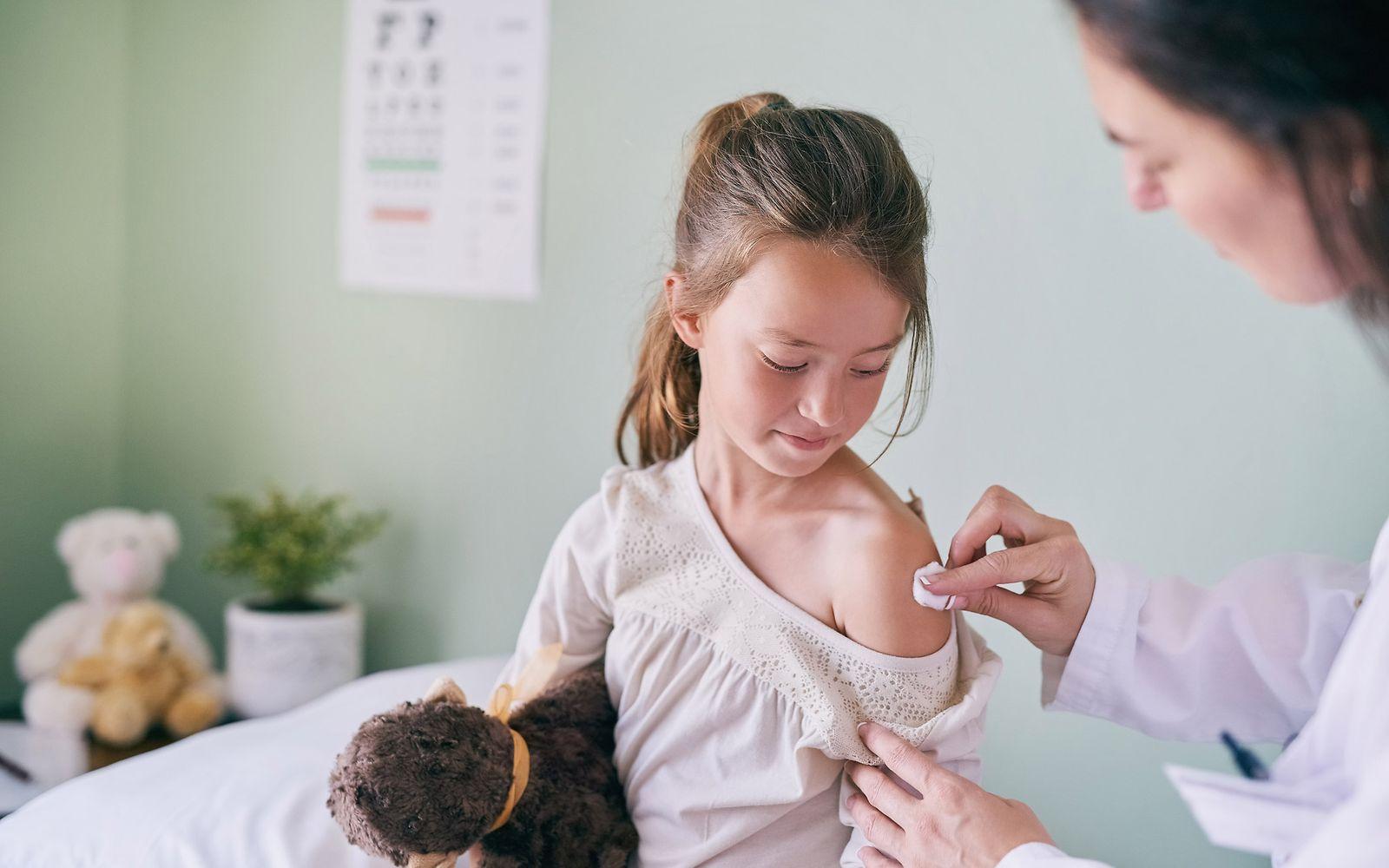 Bild: Impfungen für Kinder: Ärztin tupft Schulter eines Mädchens ab und bereitet sie für Injektion vor.