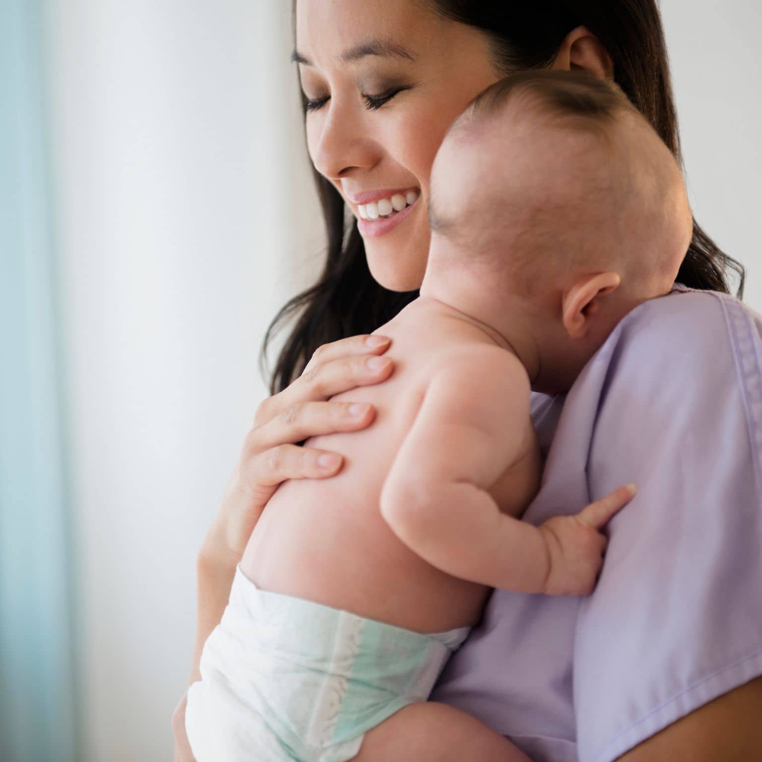 Bild: Asiatische Frau hält ein Baby auf dem Arm und sieht zufrieden aus.