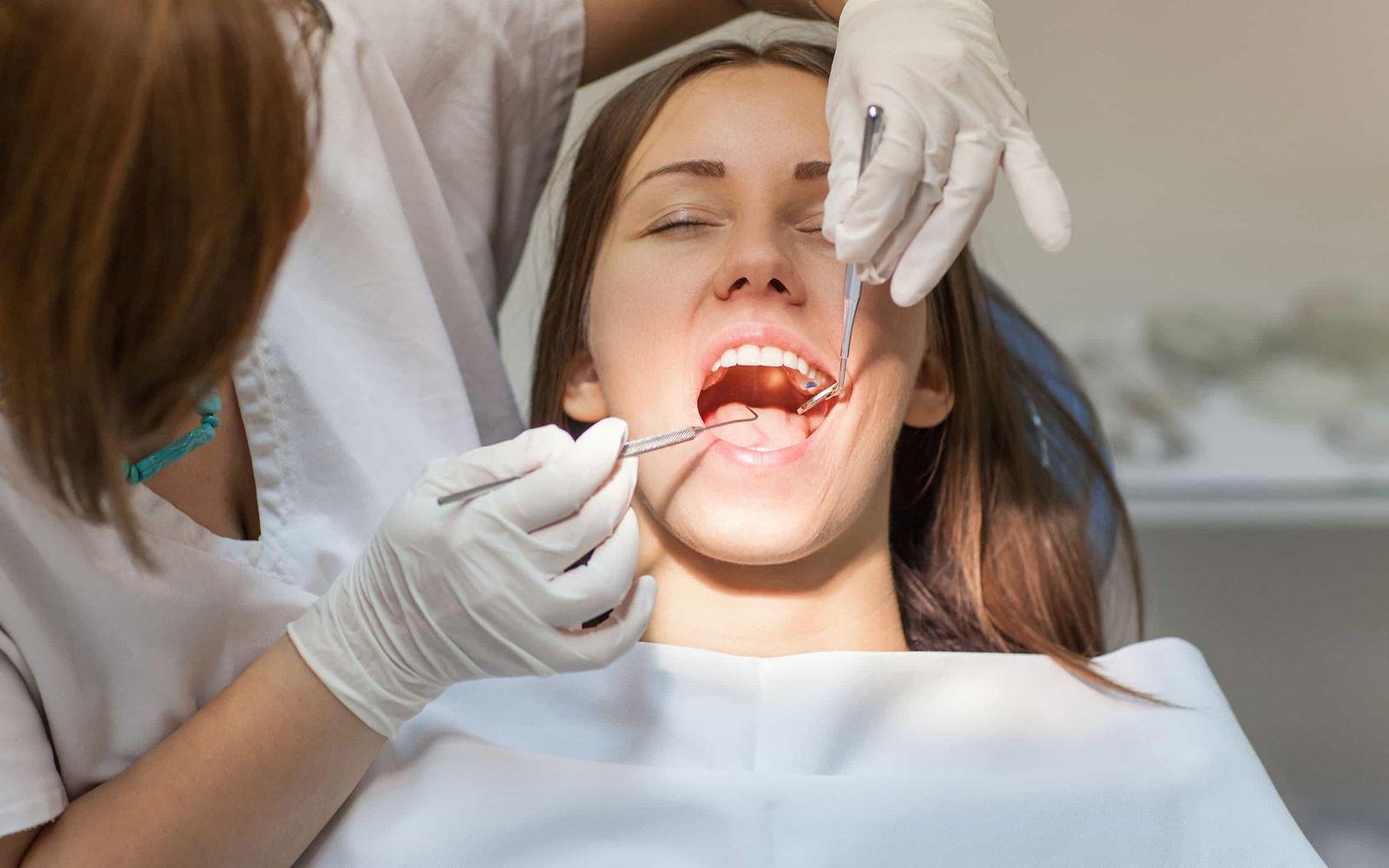 Bild: Eine Zahnarzthelferin kontrolliert die Zähne bei einer jungen Frau.