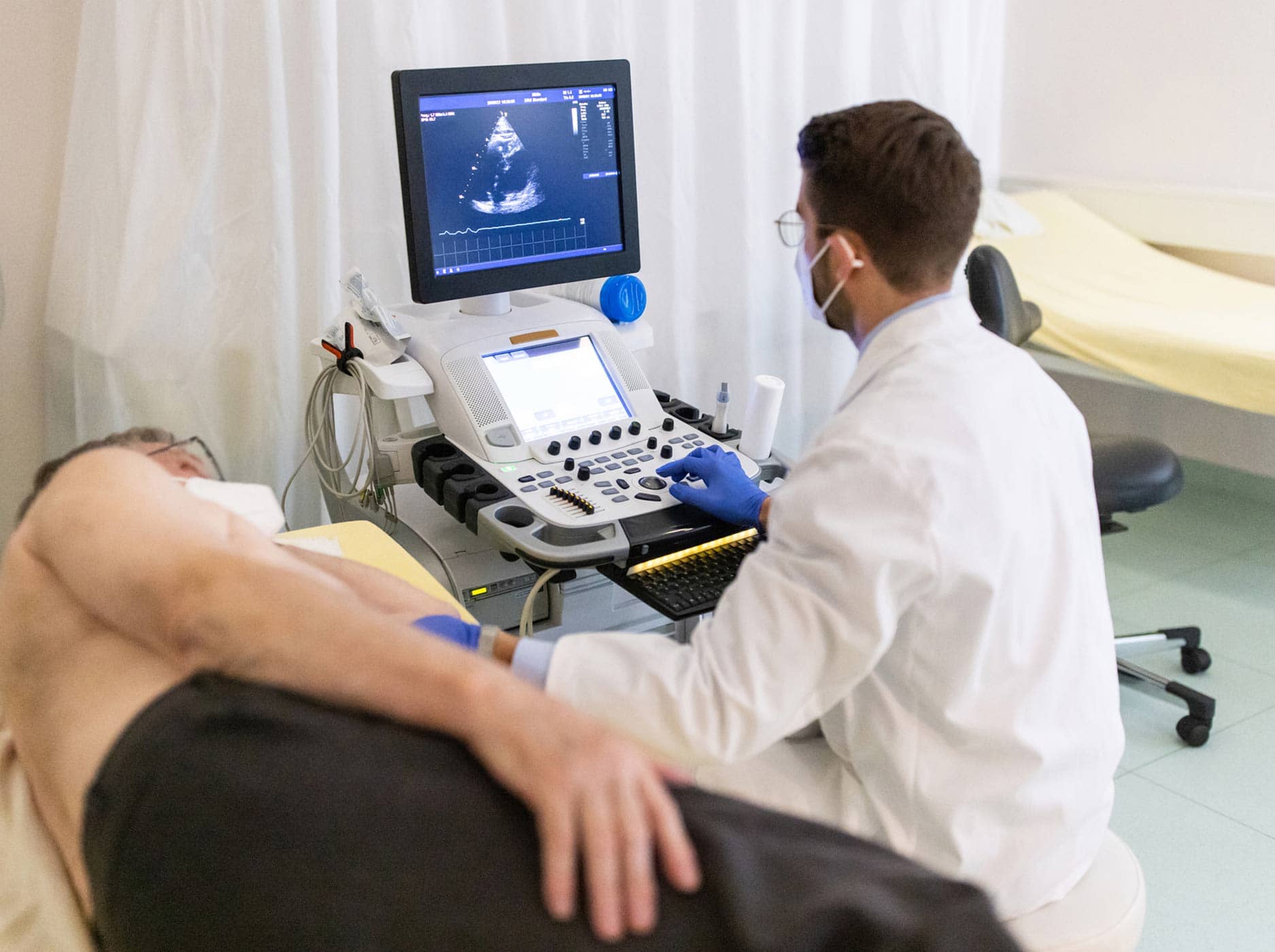Kardiologe führt bei einem älteren Mann eine Herzultraschalluntersuchung durch.