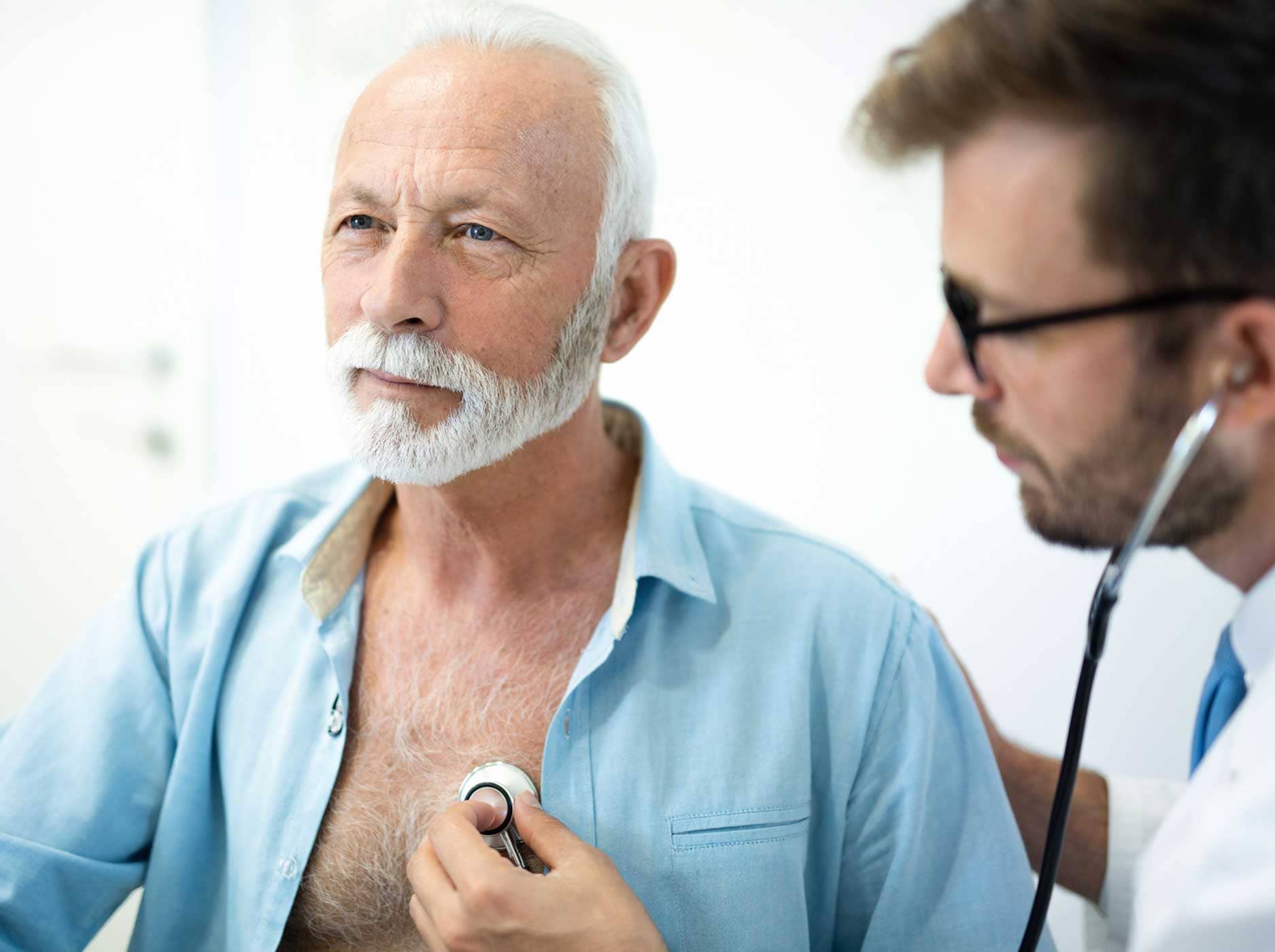 Arzt untersucht das Herz eines älteren Mannes mit dem Stethoskop.