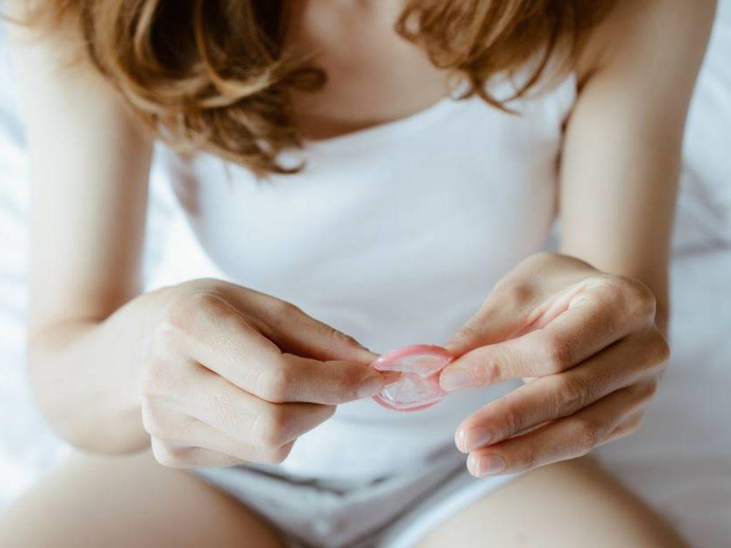 Doktorsex: Junge Frau hält Kondom in der Hand