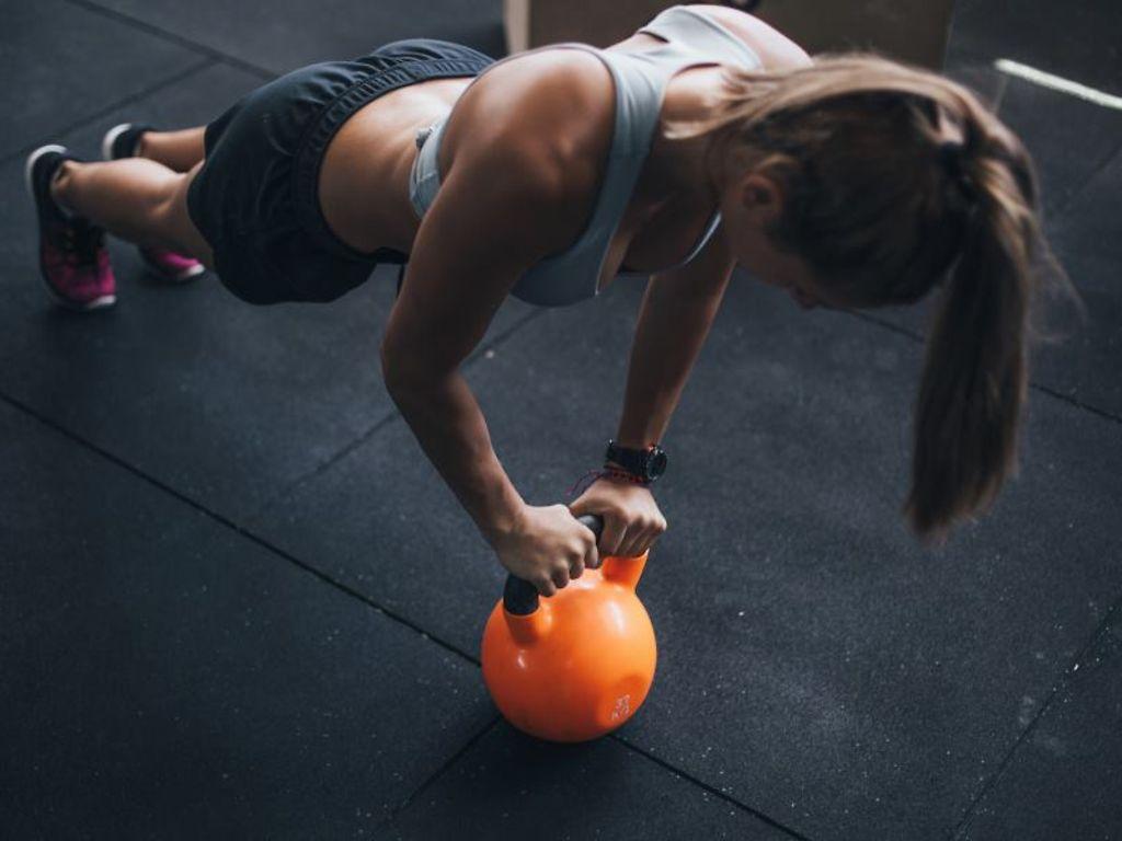 BMI: Frau macht Kraftübungen mit Kettlebell auf dem Boden