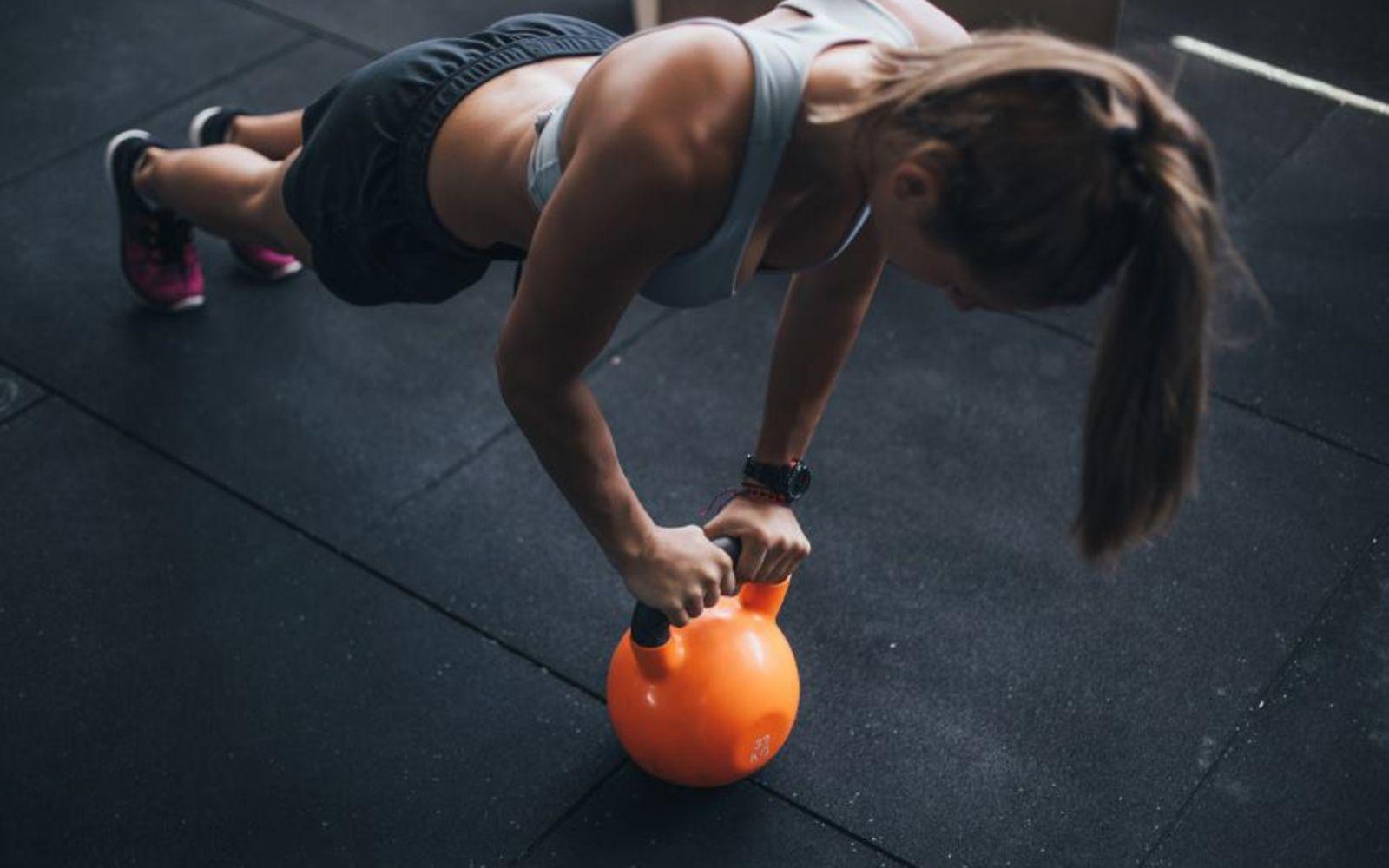 BMI: Frau macht Kraftübungen mit Kettlebell auf dem Boden