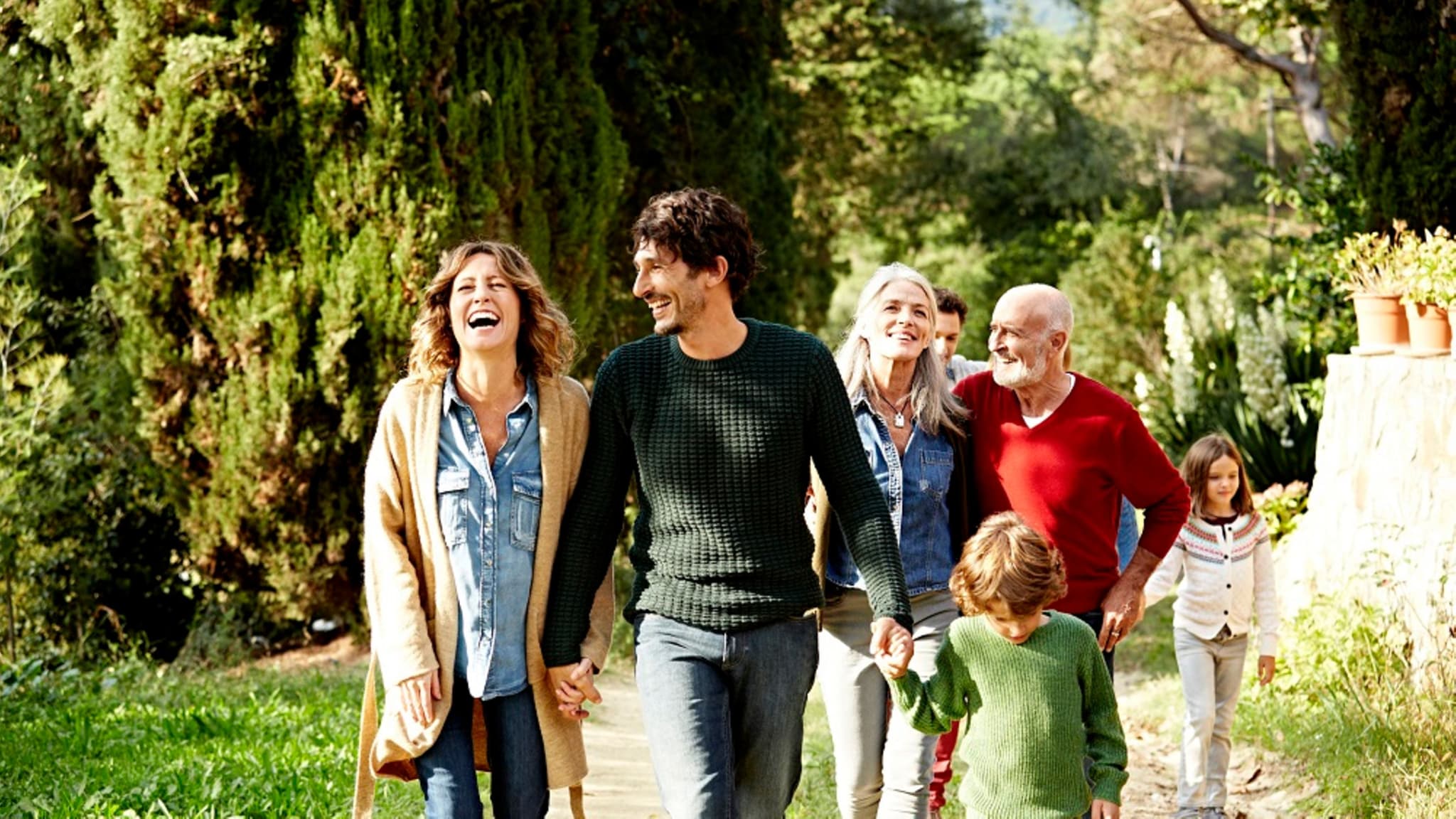 Zusatzversicherung: Eine glückliche Familie läuft durch die Natur.