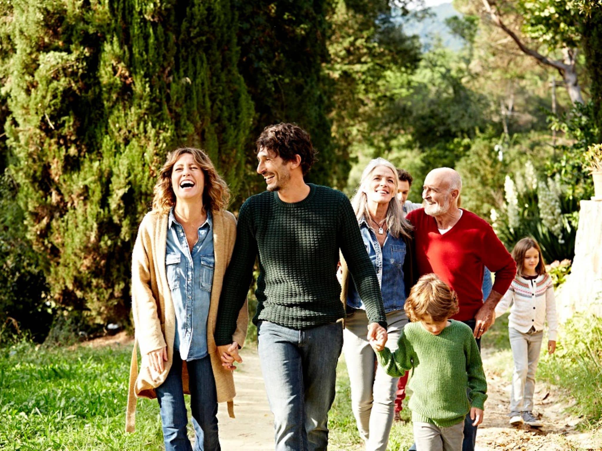 Zusatzversicherung: Eine glückliche Familie läuft durch die Natur.