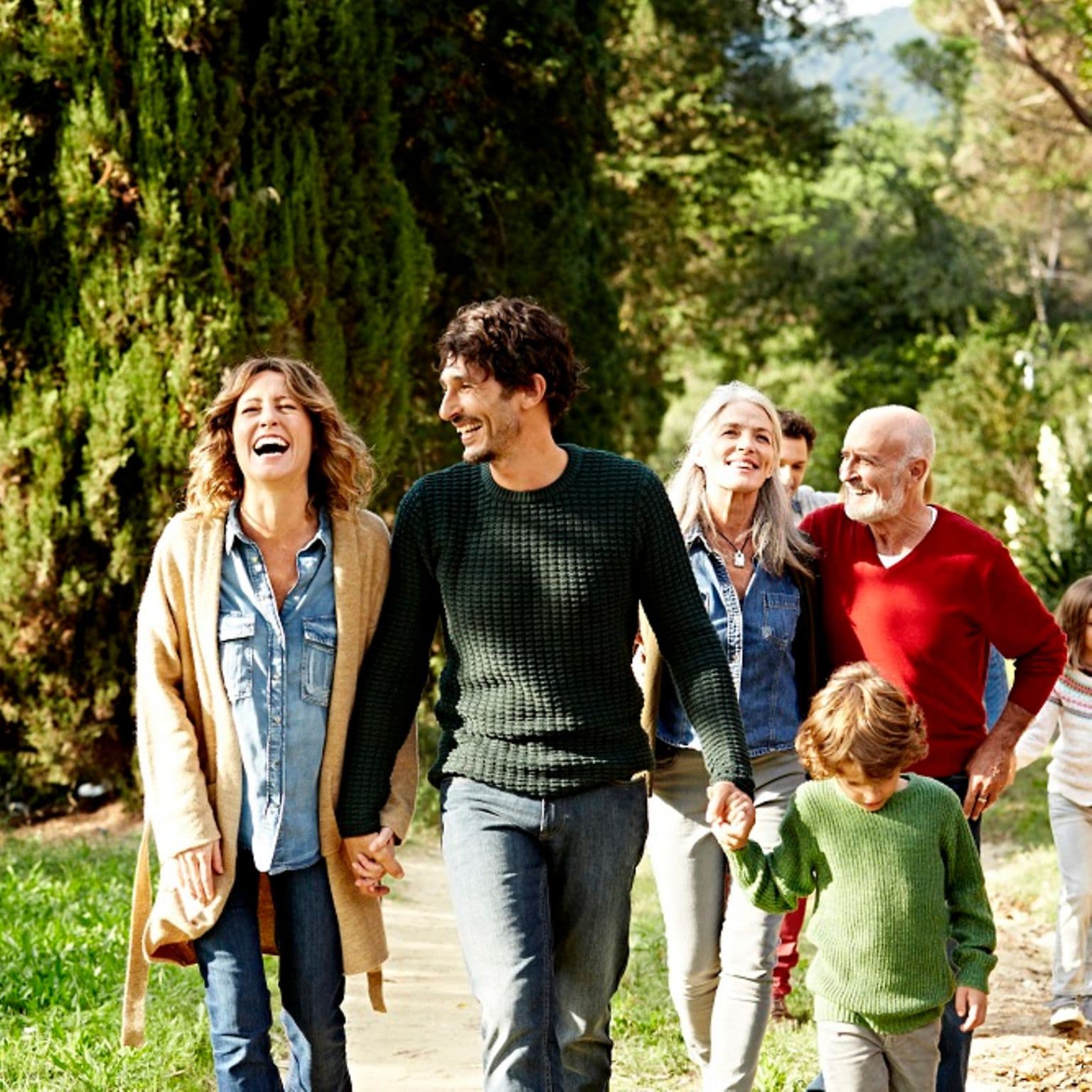 Zusatzversicherung: Eine glückliche Familie läuft durch die Natur.