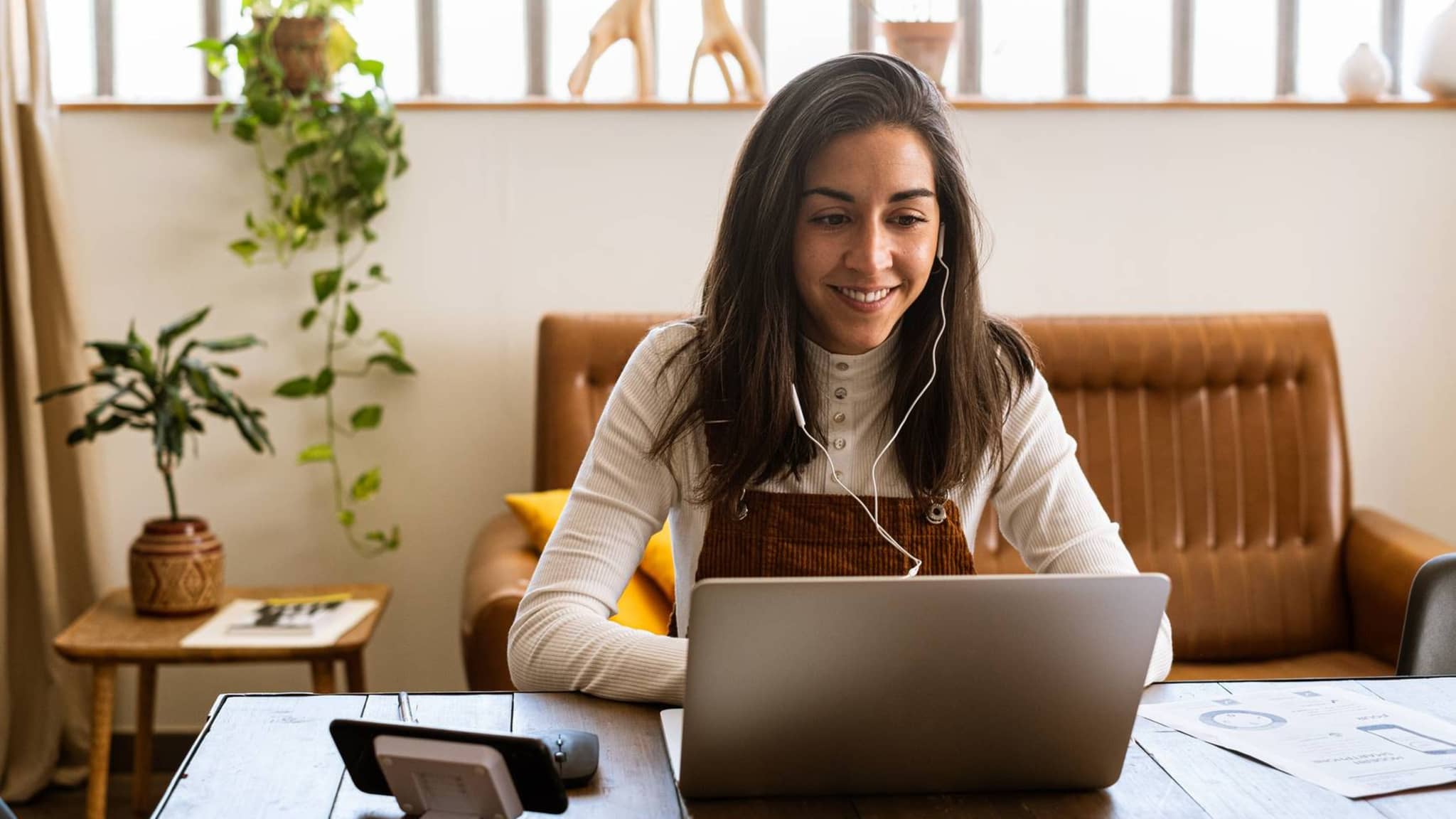 Junge Frau sitzt an ihrem Schreibtisch und schaut auf einen Laptop