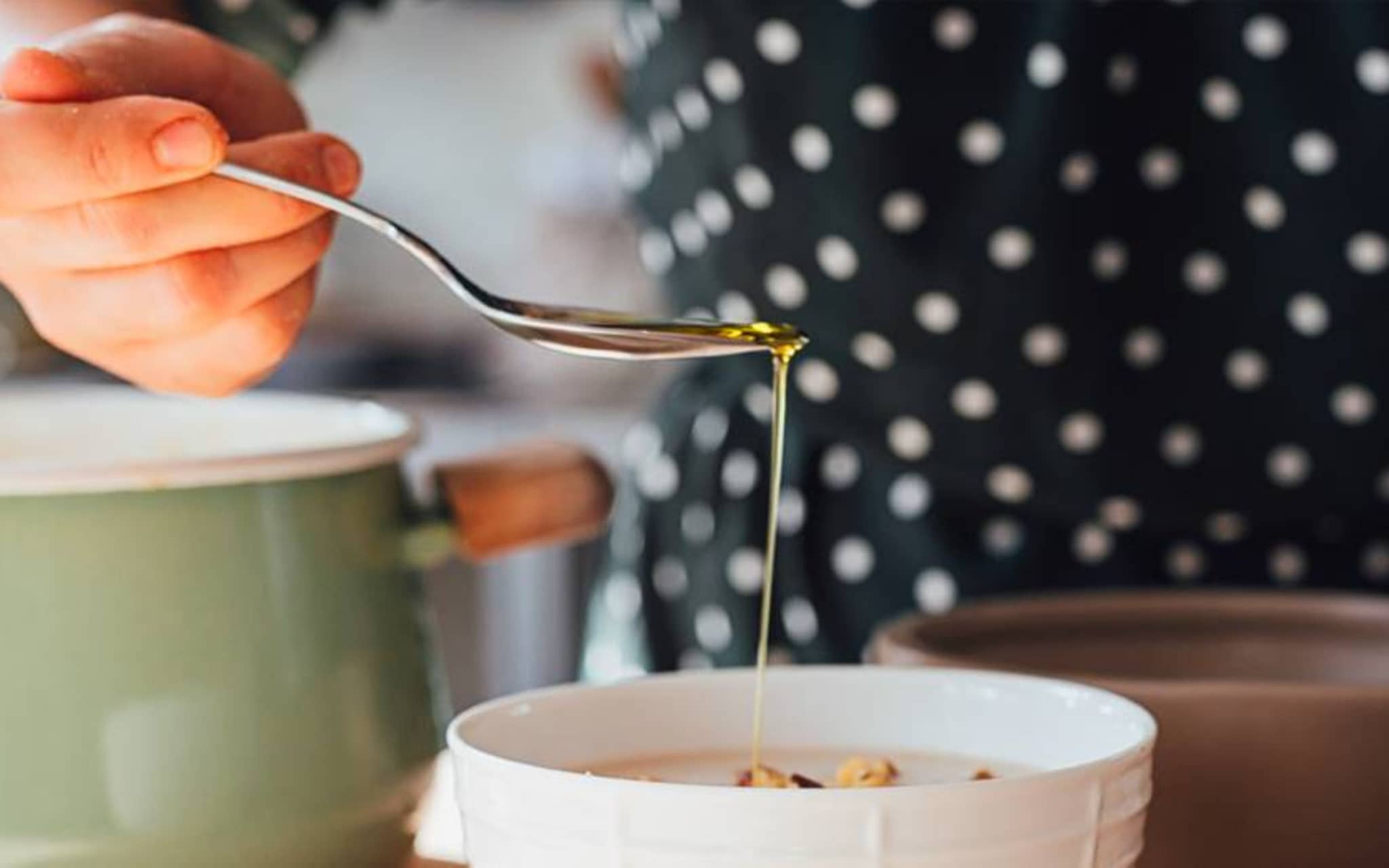 Gesunde Fette: Von einem Löffel läuft Öl in eine Suppenschale