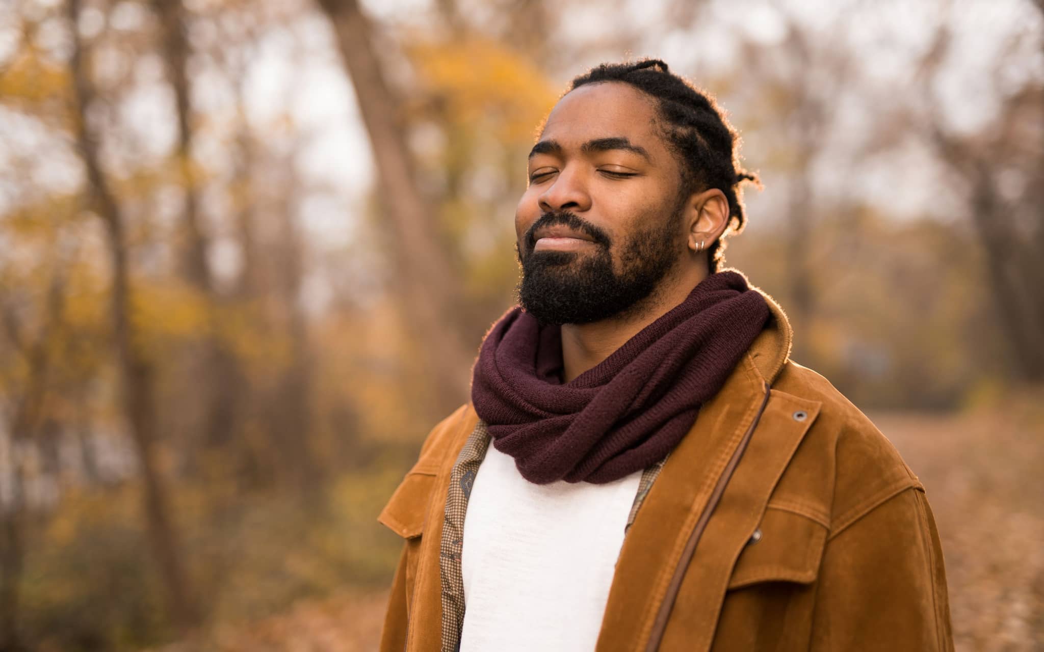 Atemübungen gegen Stress und Angst: Ein Mann steht im Wald und atmet bewusst