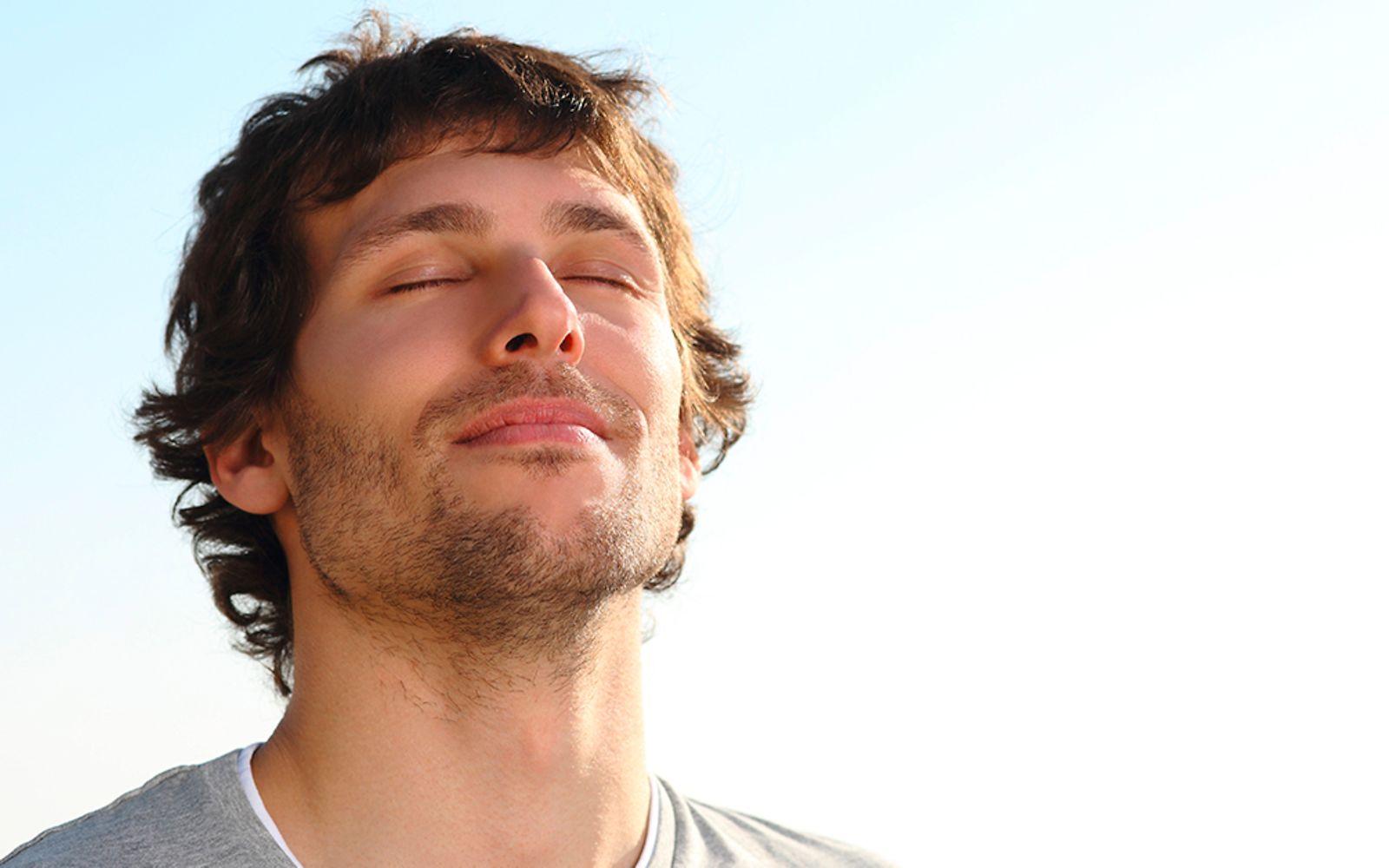 Atemtechnik: Ein Mann atmet mit geschlossenen Augen tief ein