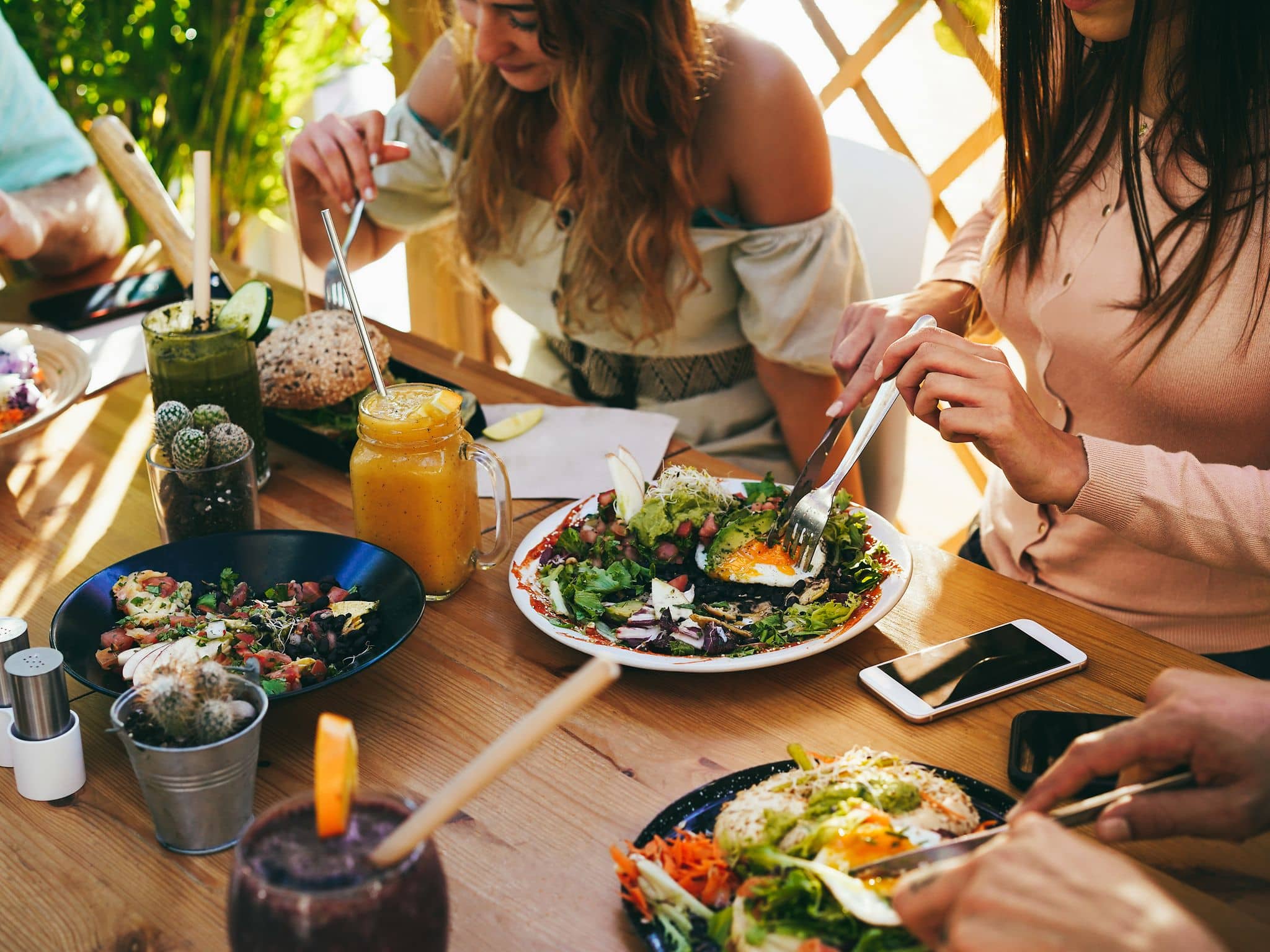 Fleischersatz: Freunde sitzen am Tisch und essen gemeinsam gesundes Essen.