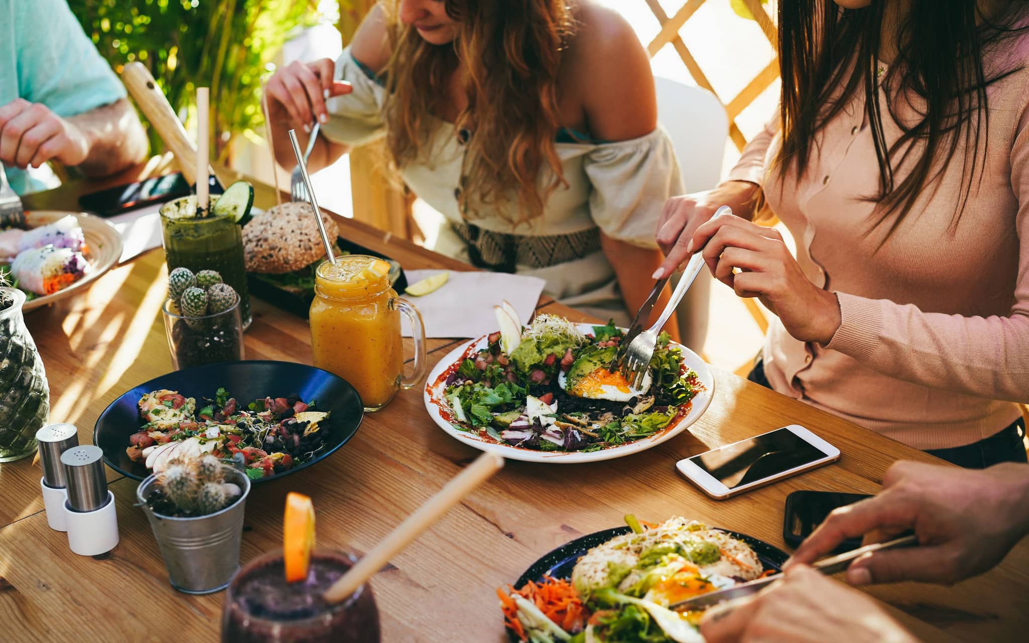 Fleischersatz: Freunde sitzen am Tisch und essen gemeinsam gesundes Essen.