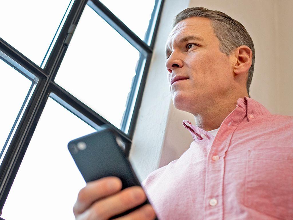 Digital Detox: Patric Heizmann hält Smartphone in der Hand und blickt aus dem Fenster