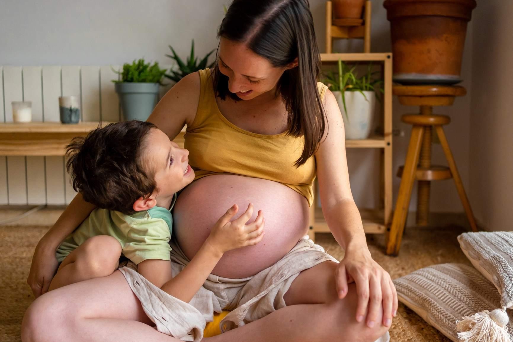 Mutterschaftsgeld: Schwangere Frau kuschelt mit Kind.