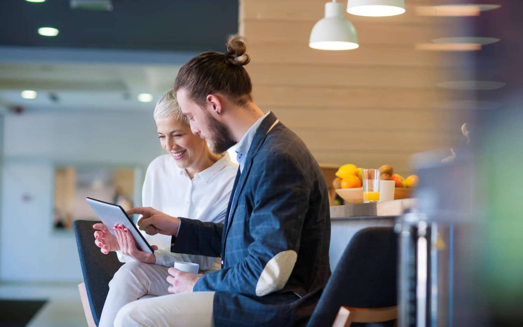 Patientenschulung Ernährung: Ältere Frau und junger Mann nutzen digitales Tablet in einem Seminarraum.