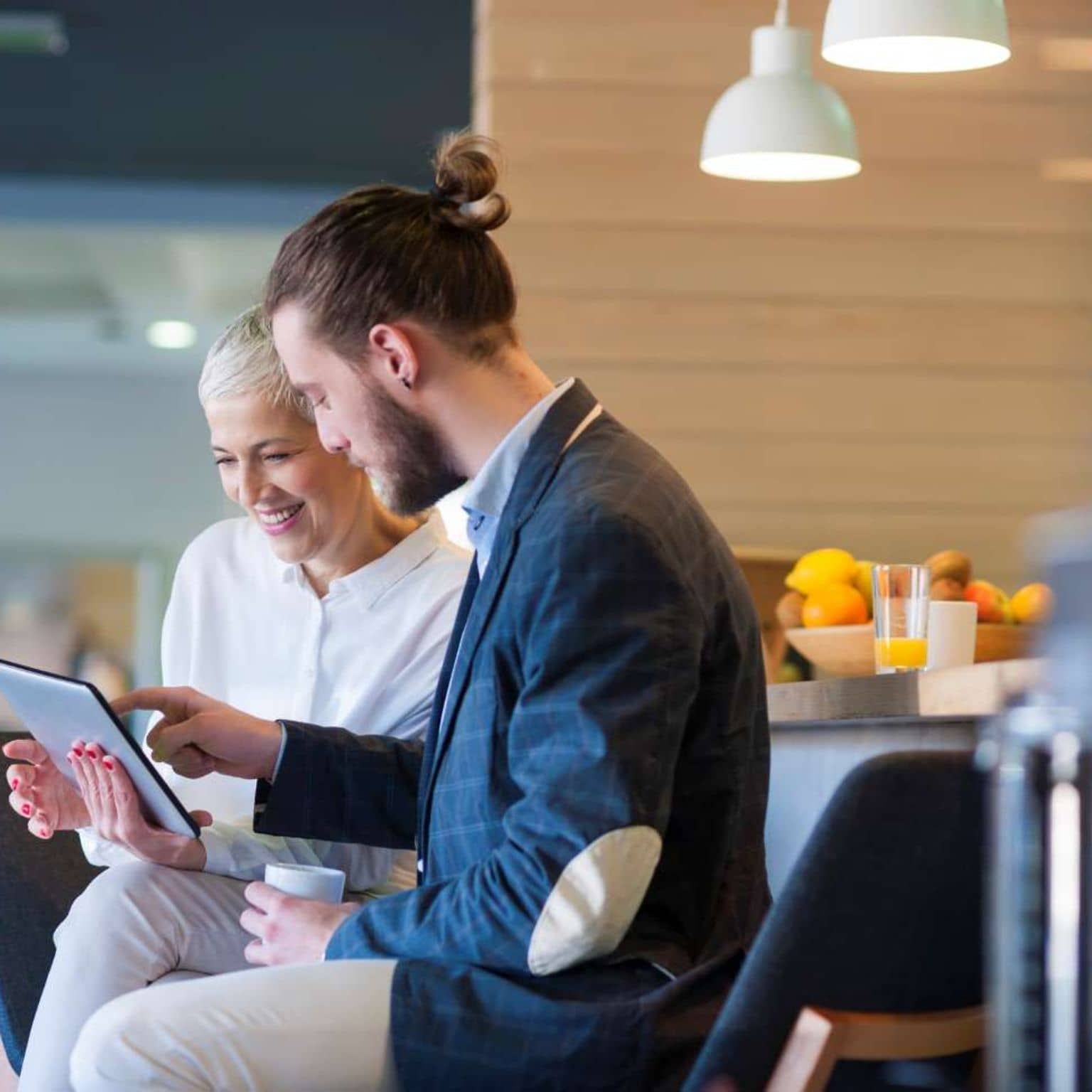 Patientenschulung Ernährung: Ältere Frau und junger Mann nutzen digitales Tablet in einem Seminarraum.