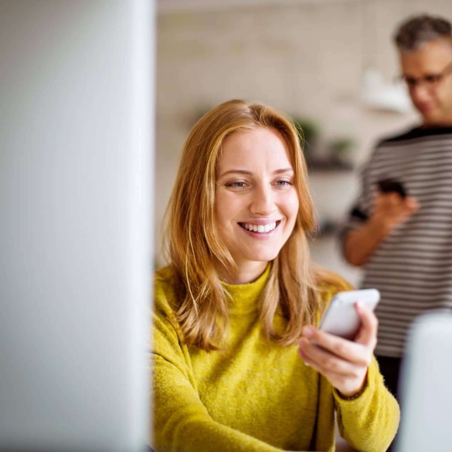 Meine DAK: Frau nutzt lächelnd Smartphone und Laptop