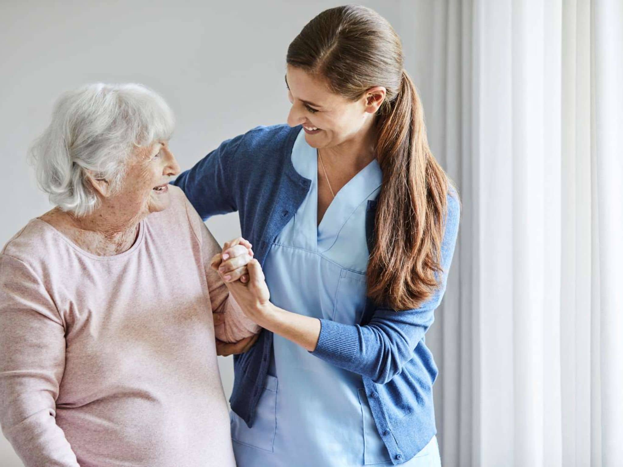 Pflege in Pflegeheimen: Pflegerin unterstützt ältere Frau beim Gehen.