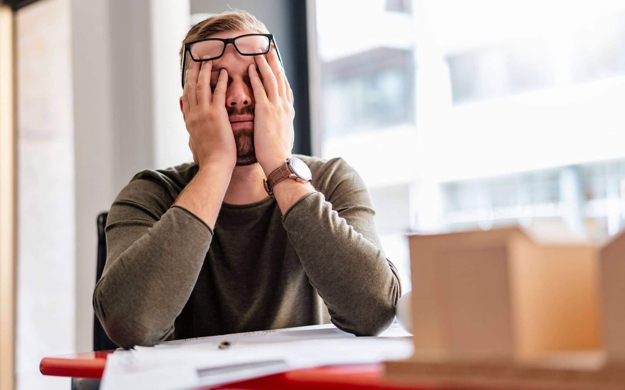 Ein erschöpfter Mitarbeiter reibt sich die Augen