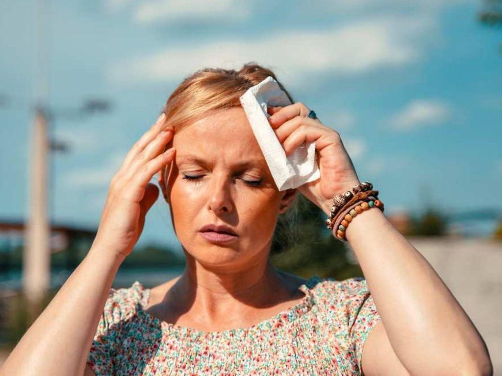 Symbolbild Hitzewelle: Eine Frau tupft sich die Schläfen ab
