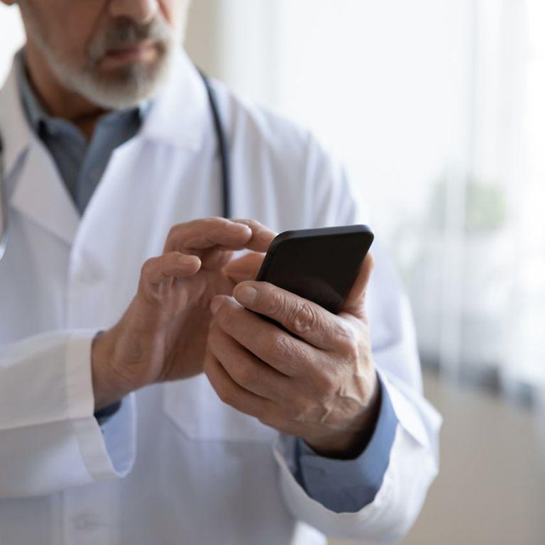 Symbolfoto elektronische Patientenakte: Arzt schaut auf Handy.