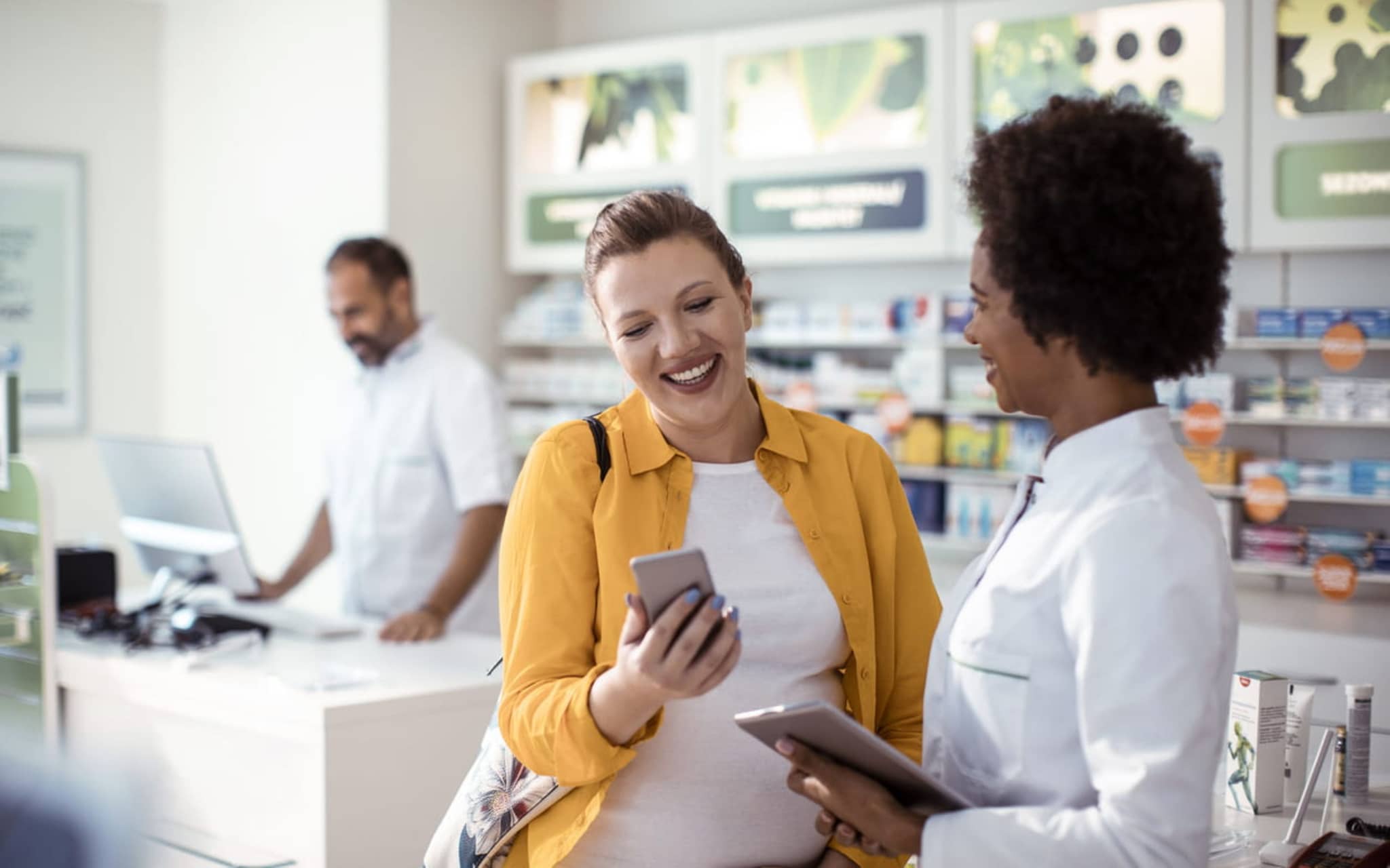 Symbolbild E-Rezept: Kundin in einer Apotheke mit Handy.