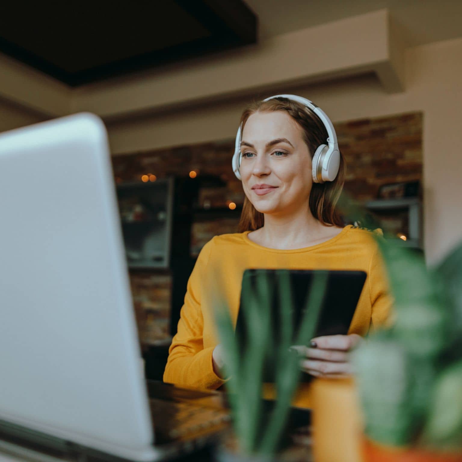 Symbolbild: Frau mit Kopfhörern am Laptop nutzt die Videoberatung der DAK-Gesundheit.