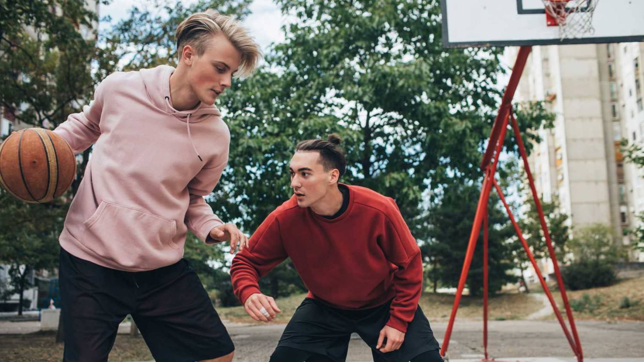 Zwei Jugendliche spielen draußen Basketball