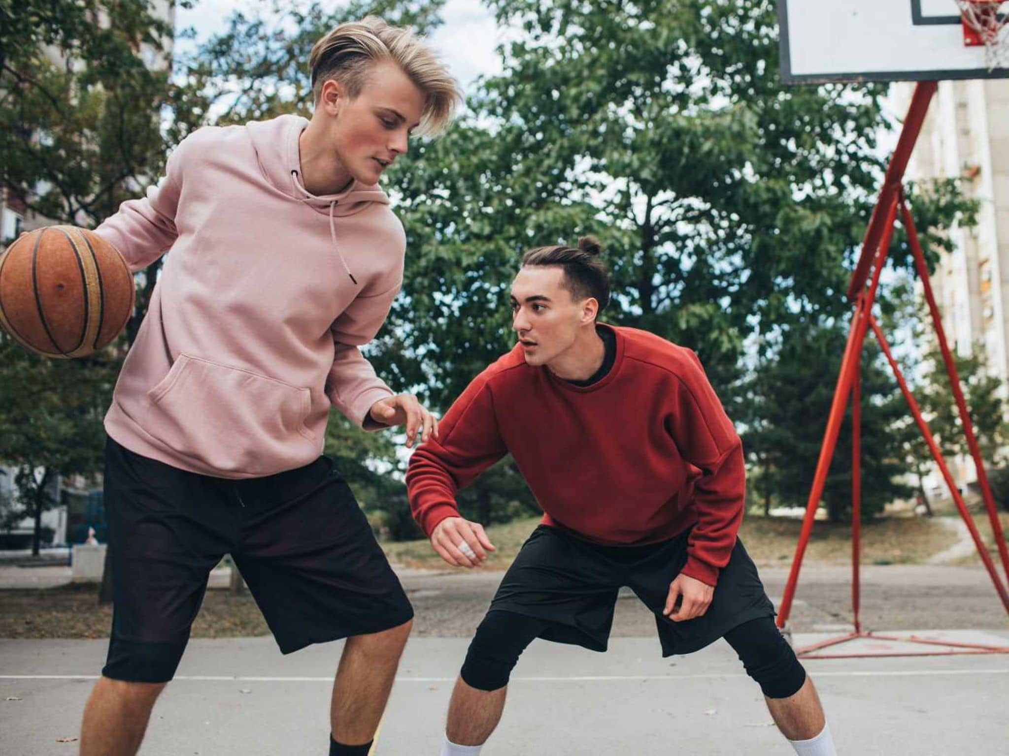 Zwei Jugendliche spielen draußen Basketball