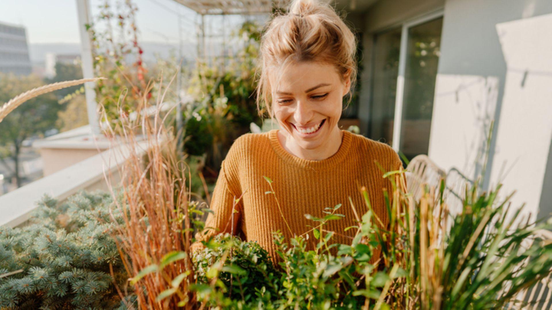 Persönliche Entwicklung: glückliche Frau genießt Pflanzen auf einem Balkon