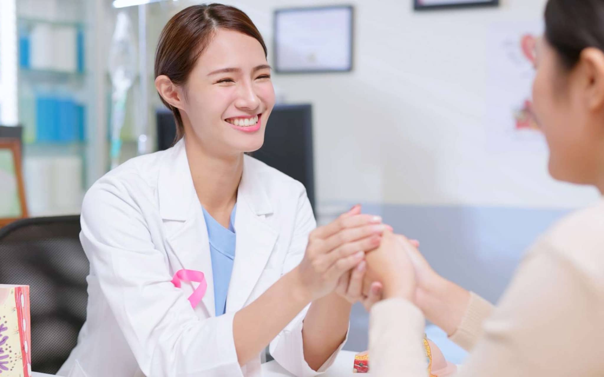 Discovering Hands: Eine junge Ärztin hält die Hand einer Patientin.