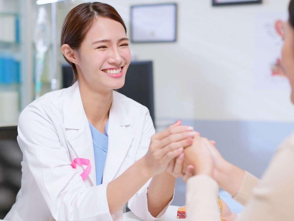 Discovering Hands: Eine junge Ärztin hält die Hand einer Patientin.
