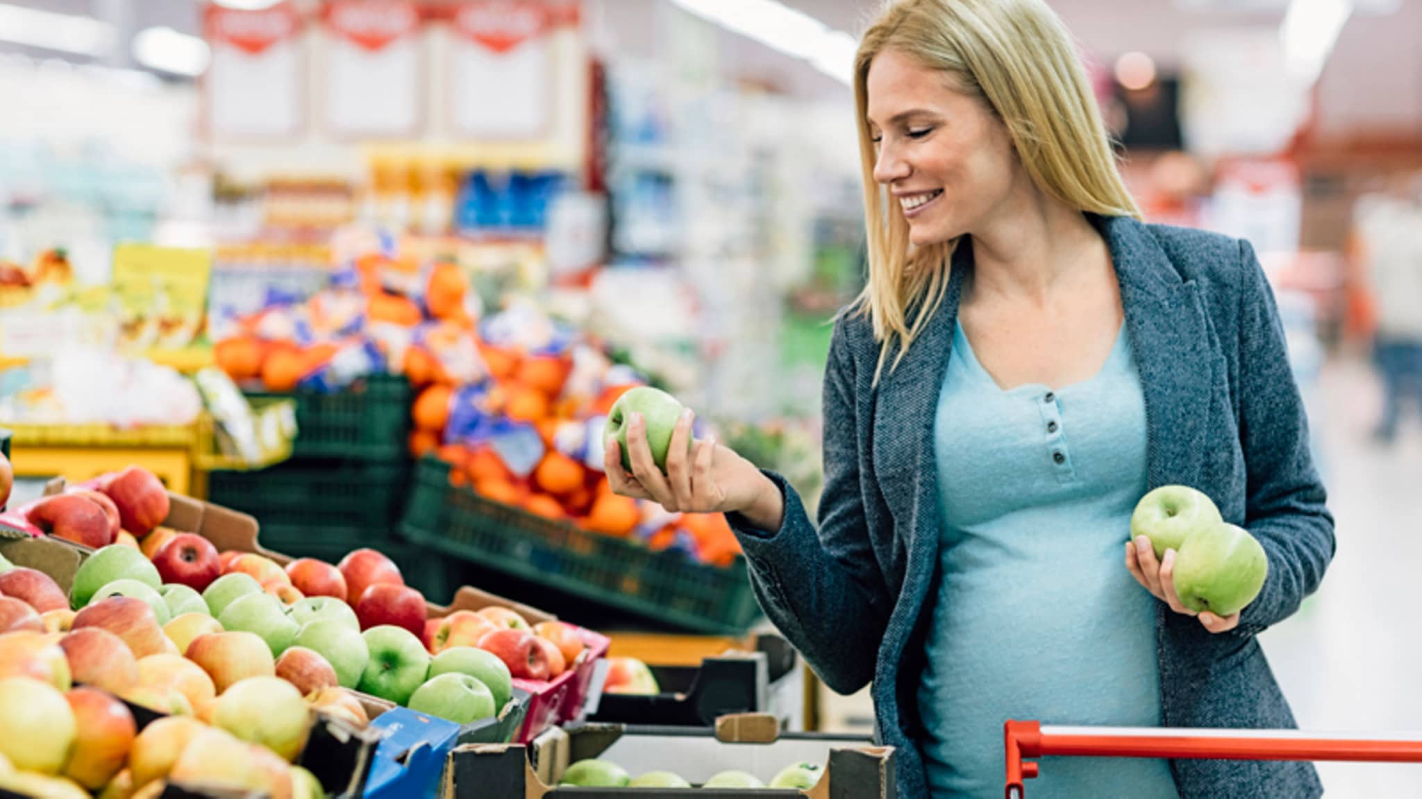 Eine Schwanger kauft Äpfel in der Obstabteilung eines Supermarkts