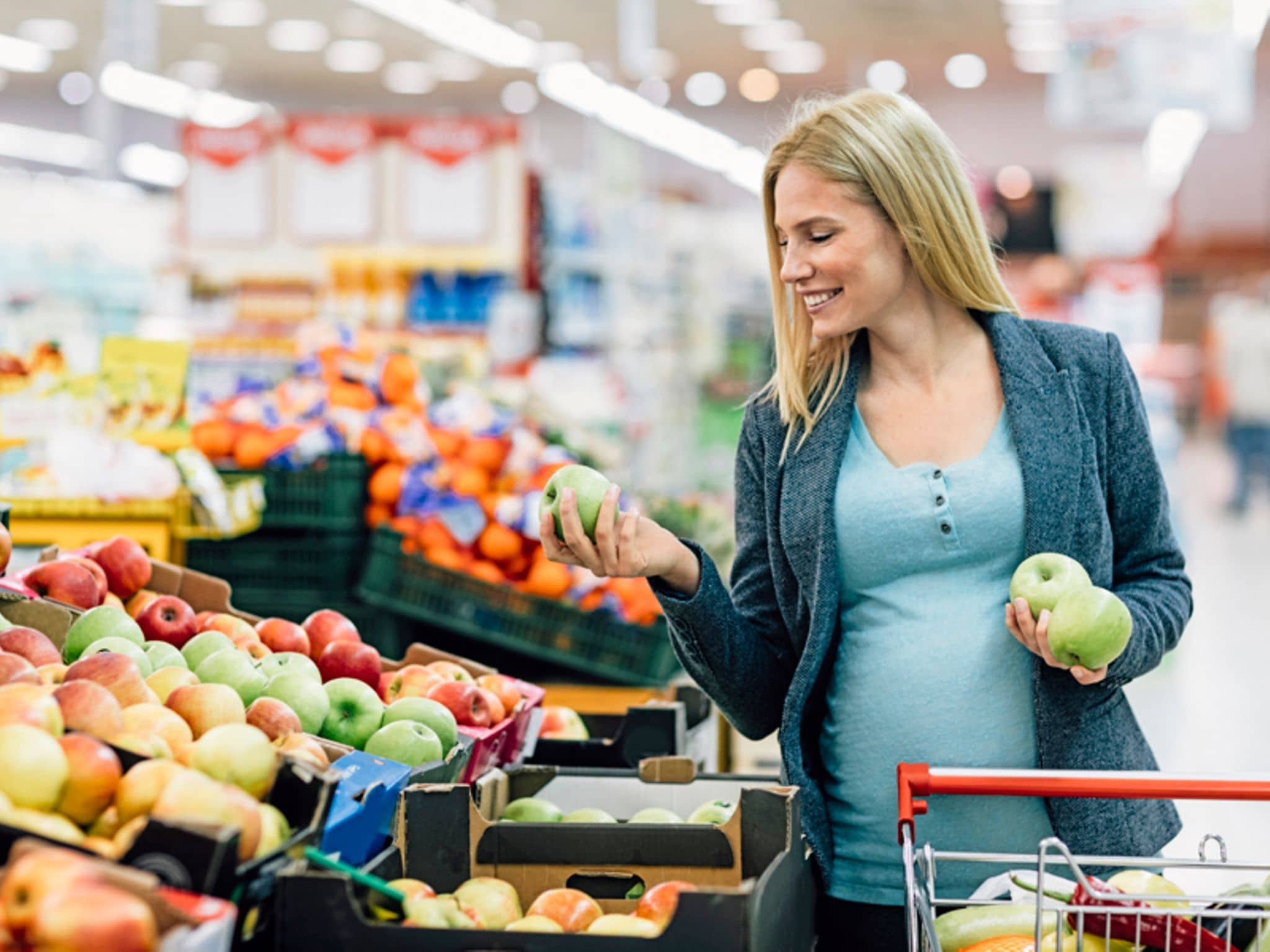 Eine Schwanger kauft Äpfel in der Obstabteilung eines Supermarkts
