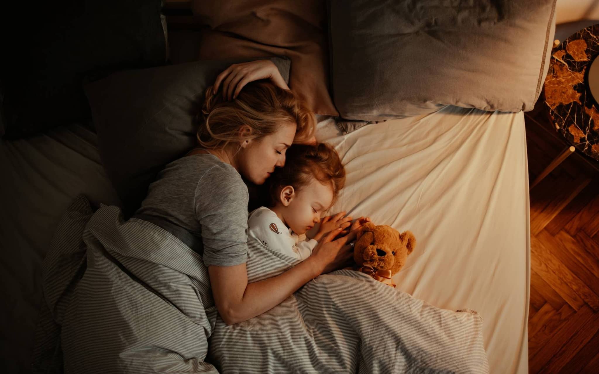 Einschlaftipps Kinder: Mutter kuschelt mit ihrem Baby im Bett