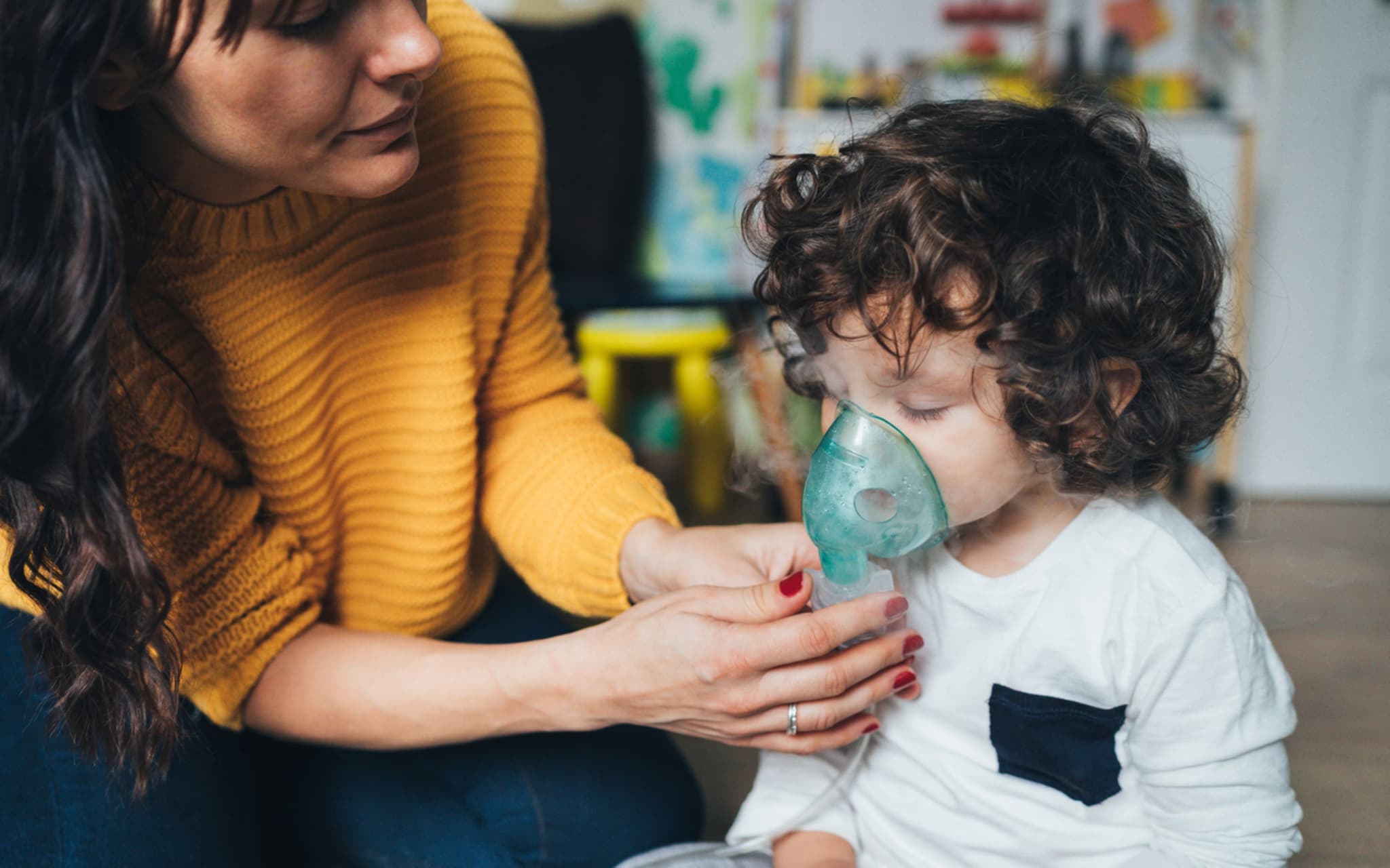 Atemwegserkrankungen bei Kindern: Mutter hilft ihrem Kleinkind mit der Inhalationsmaske
