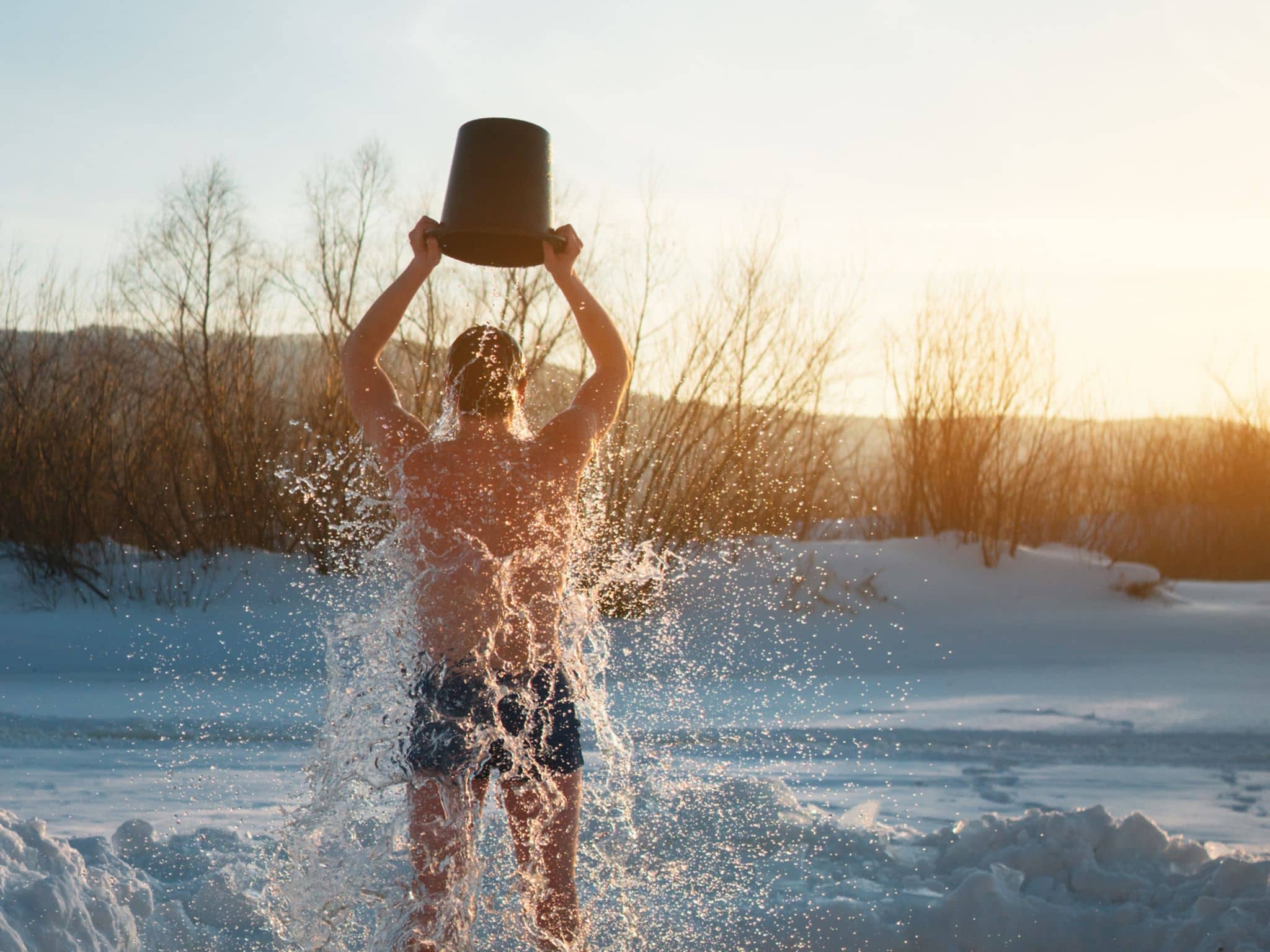 Kältetherapie: Mann übergießt sich in Winterlandschaft mit Wasser