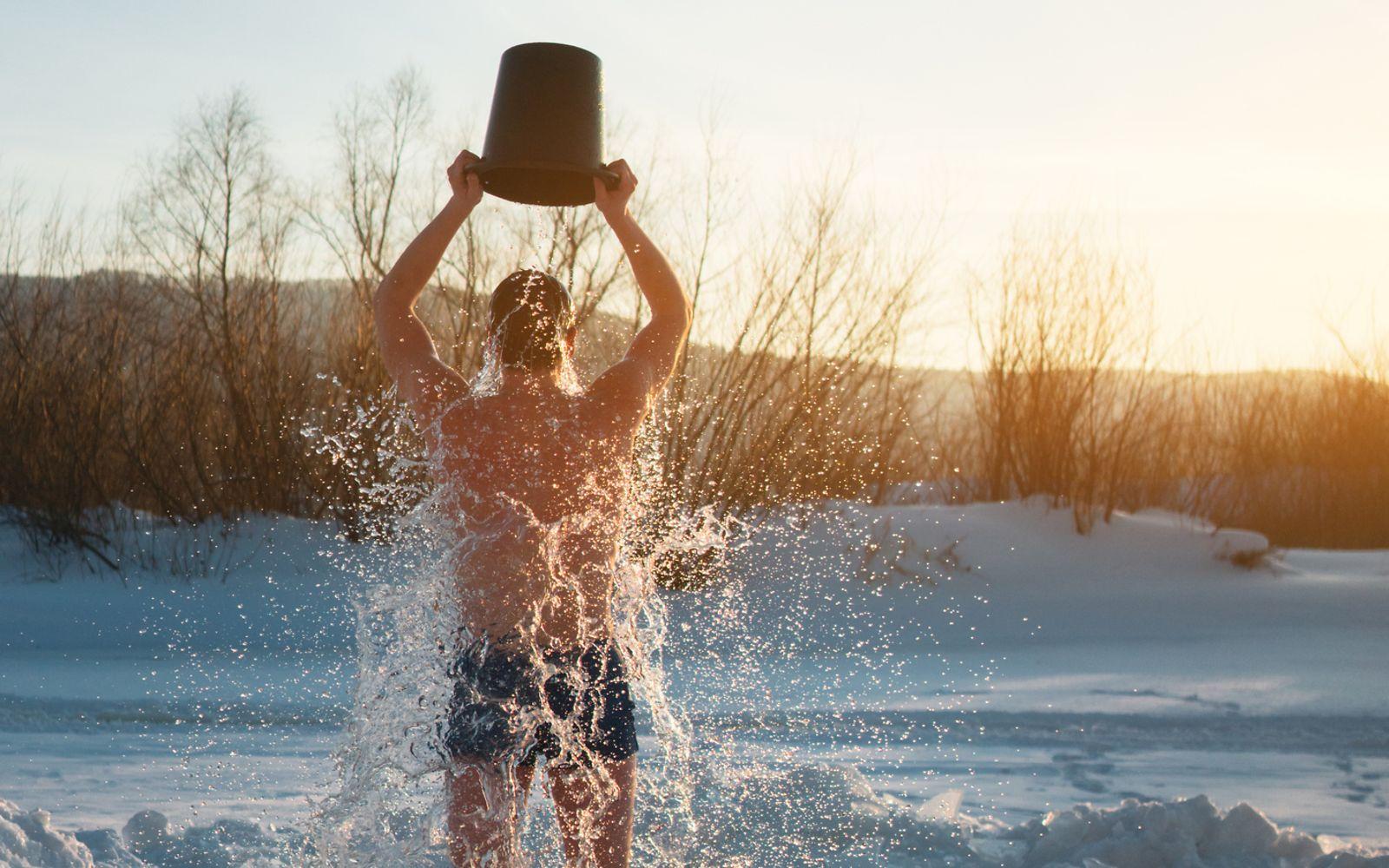 Kältetherapie: Mann übergießt sich in Winterlandschaft mit Wasser