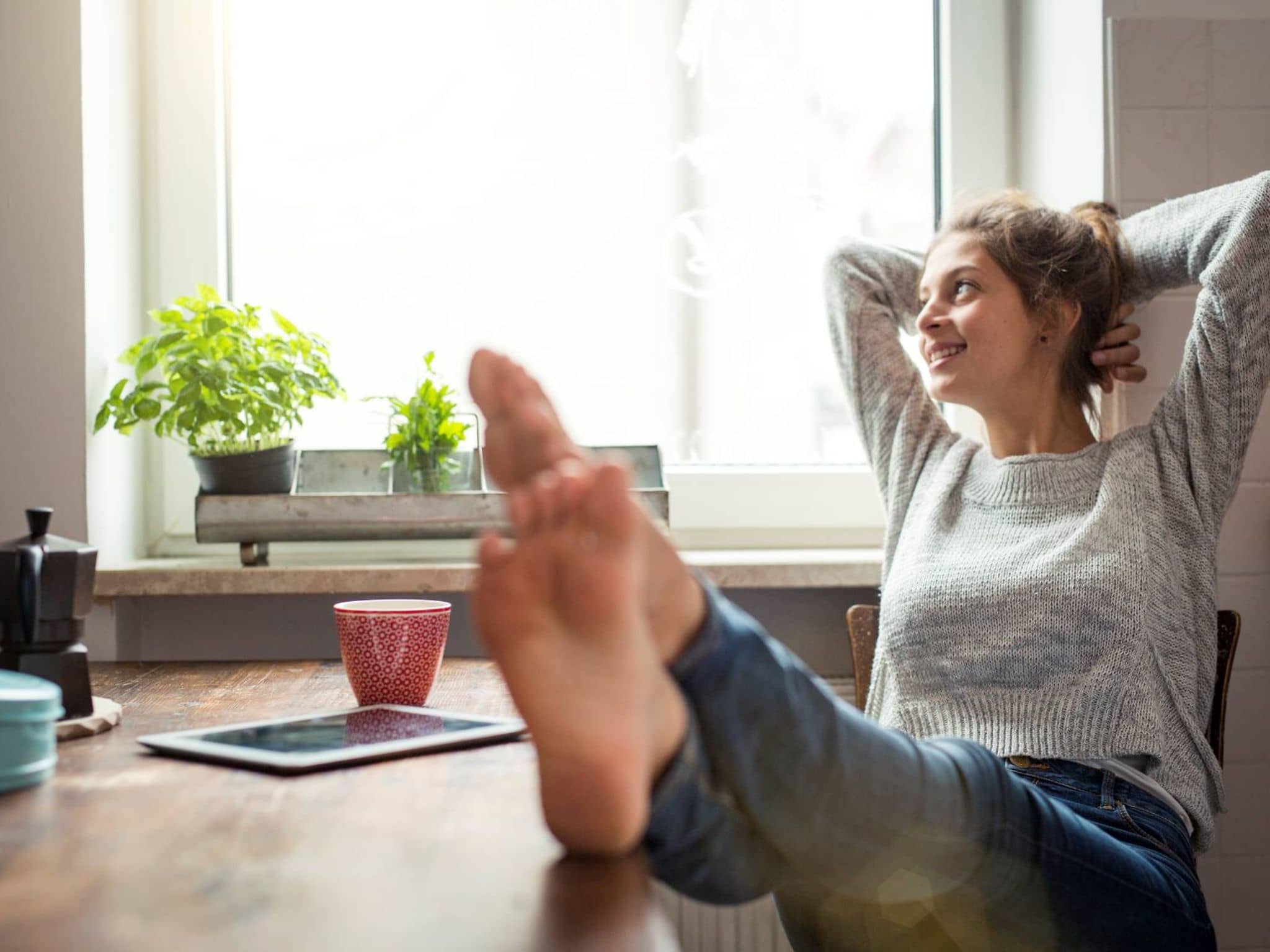 Geschwollene Beine: Frau legt die Füße auf den Tisch und entspannt sich