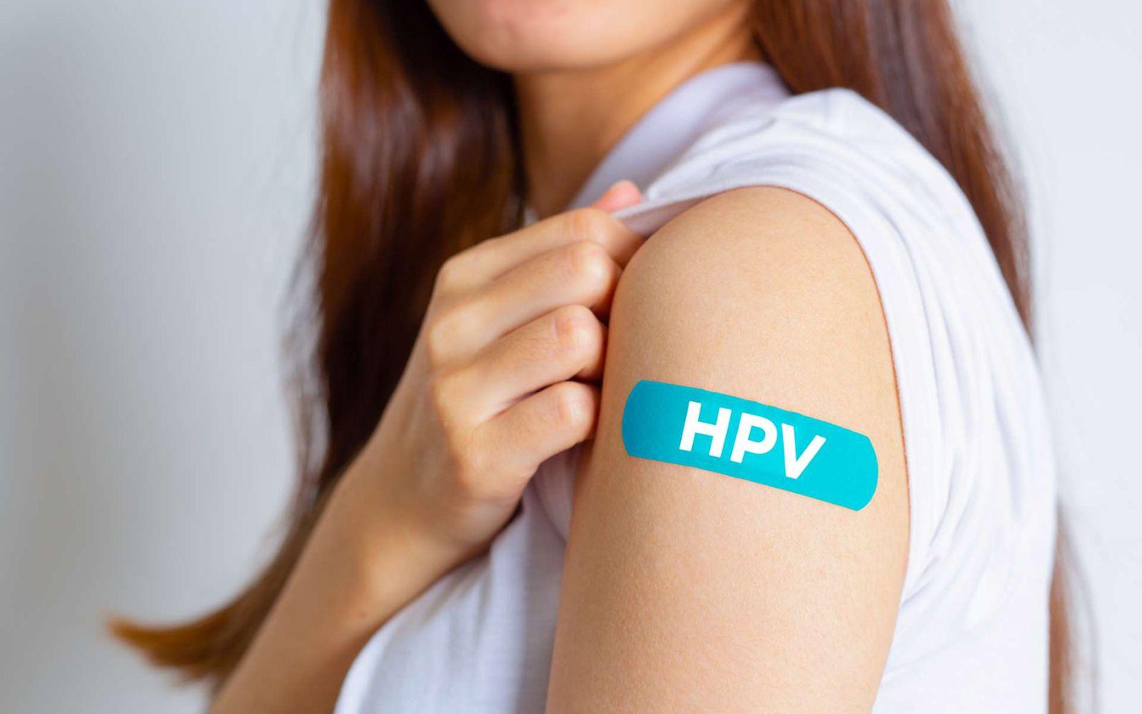 HPV-Impfungen: Junge Frau zeigt ein Pflaster auf ihrer Schulter, auf dem HPV steht.
