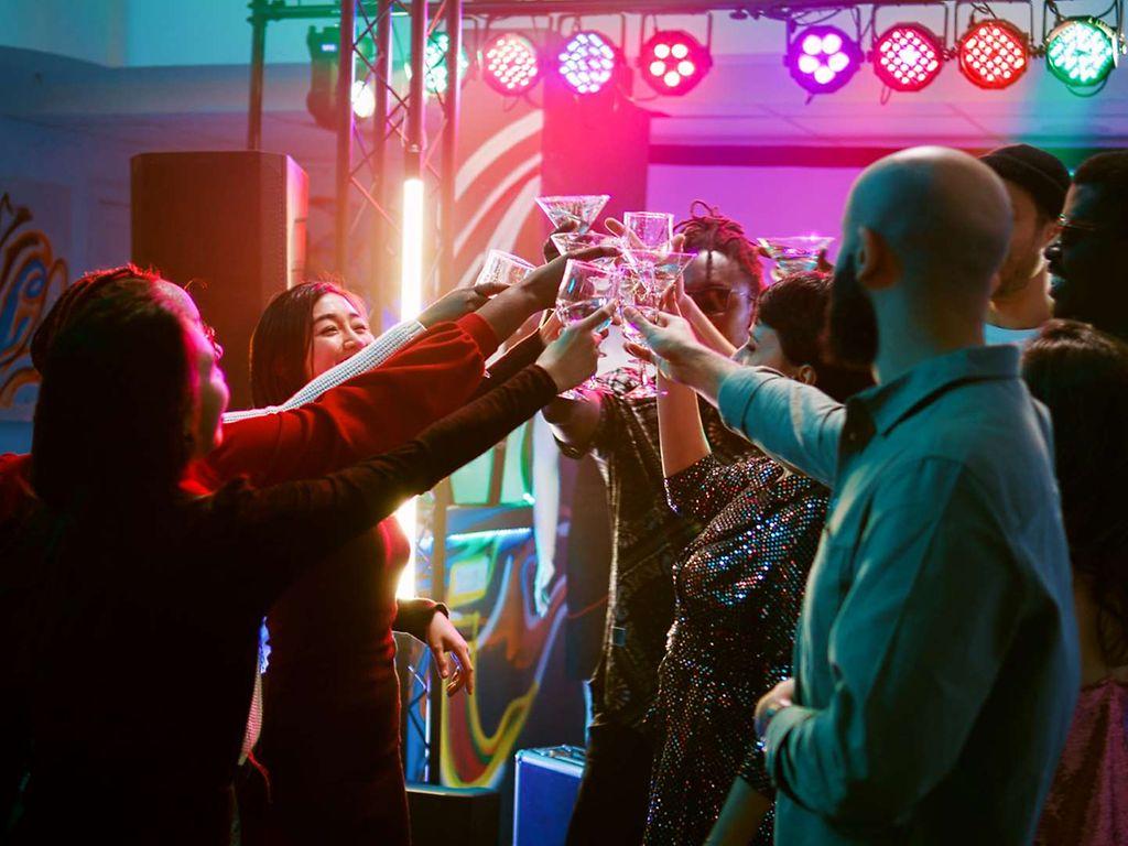Party ohne Alkohol: Partygäste stoßen auf der Tanzfläche mit ihren alkoholfreien Drinks an.